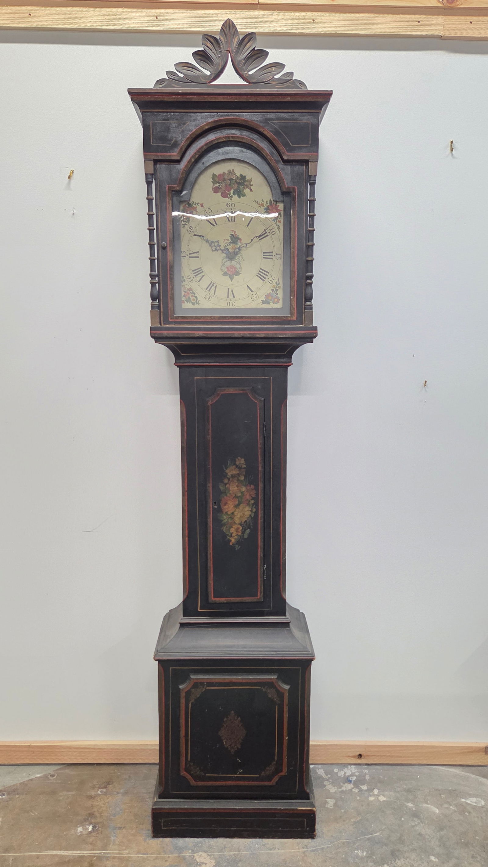 FOLK ART BLACK HAND PAINTED ANTIQUE TALL CASE CLOCK: REMAINS IN FAIR TO GOOD CONDITION, SHOWING TYPICAL WEAR. SOME CRACKING AND REPAIRS TO MOLDING. PAINT CRACKING PRESENT THROUGHOUT. HAND PAINTED CLOCK FACE SHOWING WEAR. BACK OF CLOCK FACE READS THAT IT