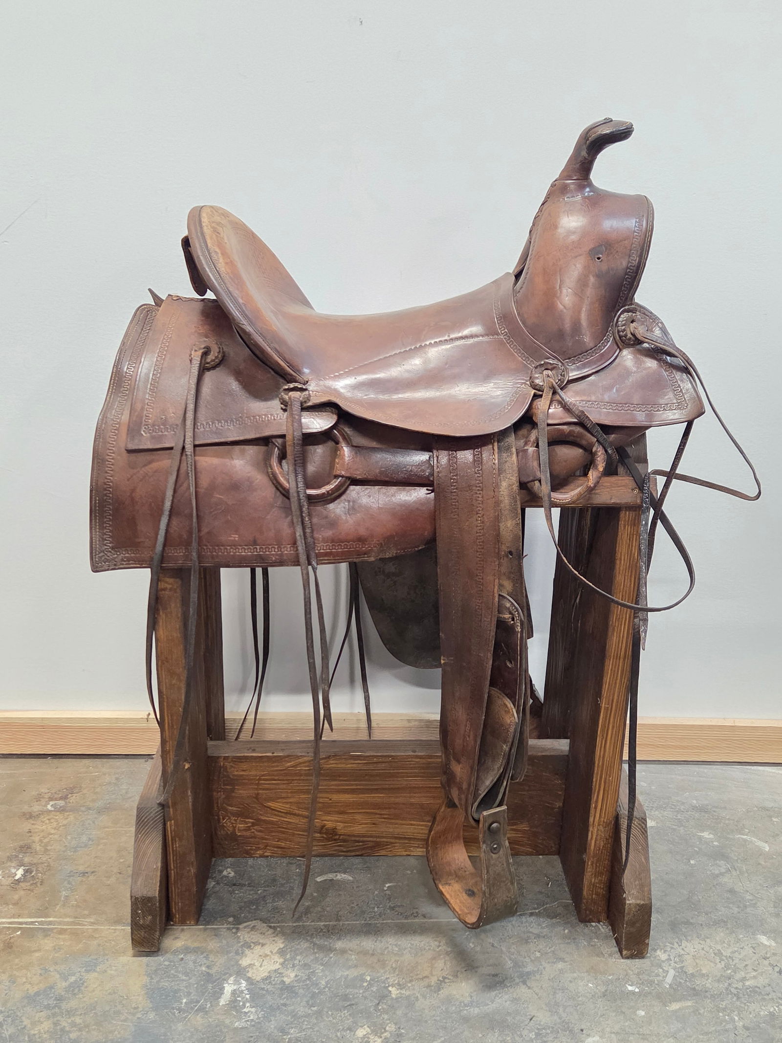 UNMARKED WESTERN LEATHER SADDLE: REMAINS IN GOOD CONDITION, SHOWING SOME TYPICAL WEAR. INCLUDES ALL AS SHOWS. STAND NOT INCLUDED.