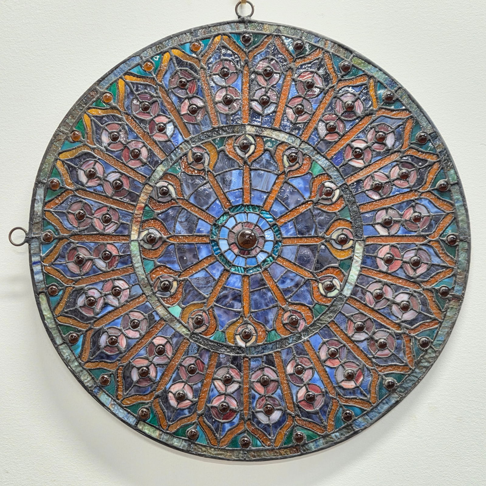 ROUND GEOMETRIC LEADED STAINED GLASS WINDOW: REMAINS IN GOOD CONDITION, SHOWING SOME TYPICAL WEAR.