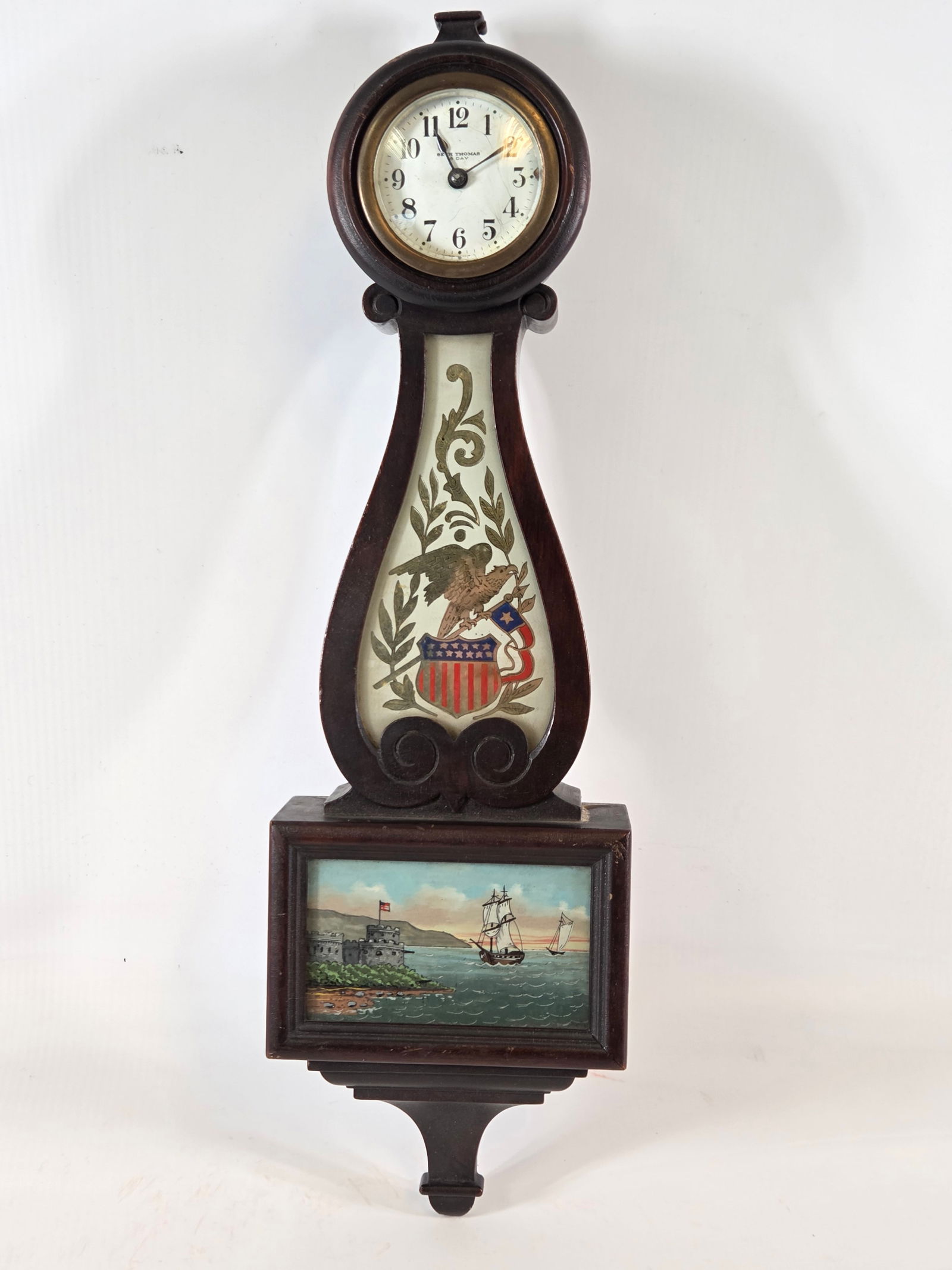 ANTIQUE SETH THOMAS REVERSE BANDED BANJO STYLE CLOCK: REVERSE PAINTED IMAGE REMAINS IN VERY GOOD CLEAN CONDITION. NICE EAGLE WITH AMERICAN FLAG & SHIELD. SAILING SHIP AT SEA NEAR FORT REVERSE PAINT IMAGE REMAINS VERY NICE. SOME SCRATCHING ON CLOCK FACE.