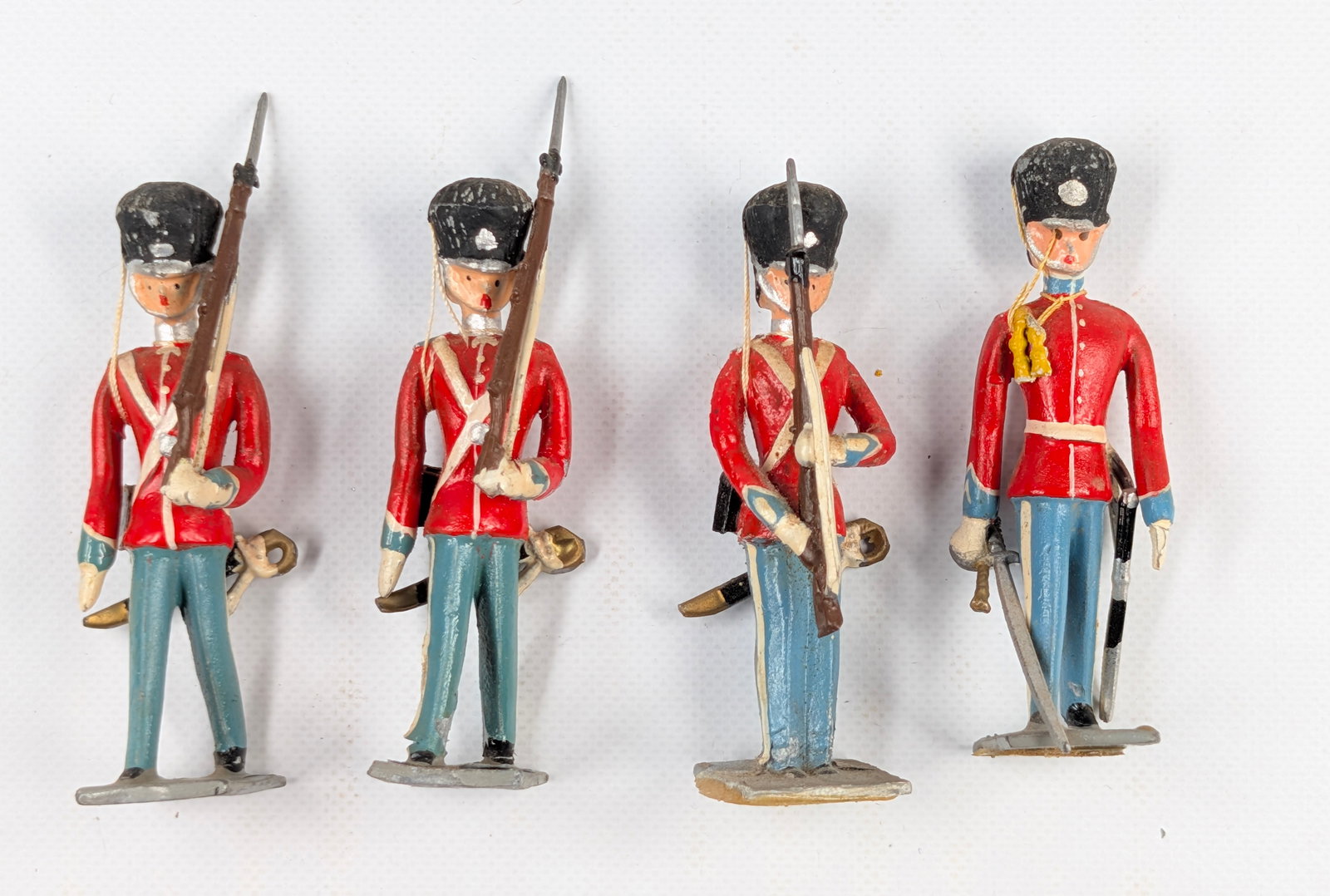 SET OF 4 UNMARKED HAND PAINTED LEAD SOLDIERS GUARDS: ALL REMAIN IN FAIR TO GOOD CONDITION, SHOWING PAINT WEAR.