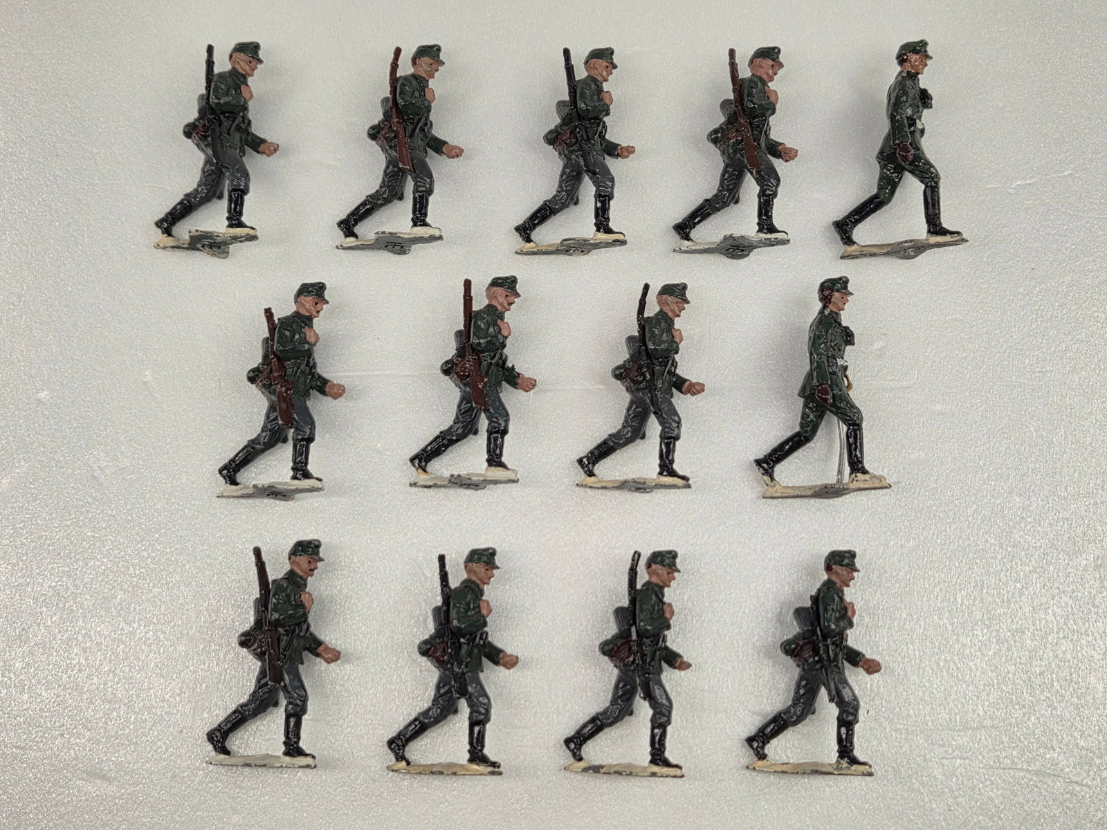 TROPHY MINIATURES SET OF 13 SOLDIERS MARCHING: ALL REMAIN IN FAIR TO GOOD CONDITION, SHOWING PAINT WEAR.