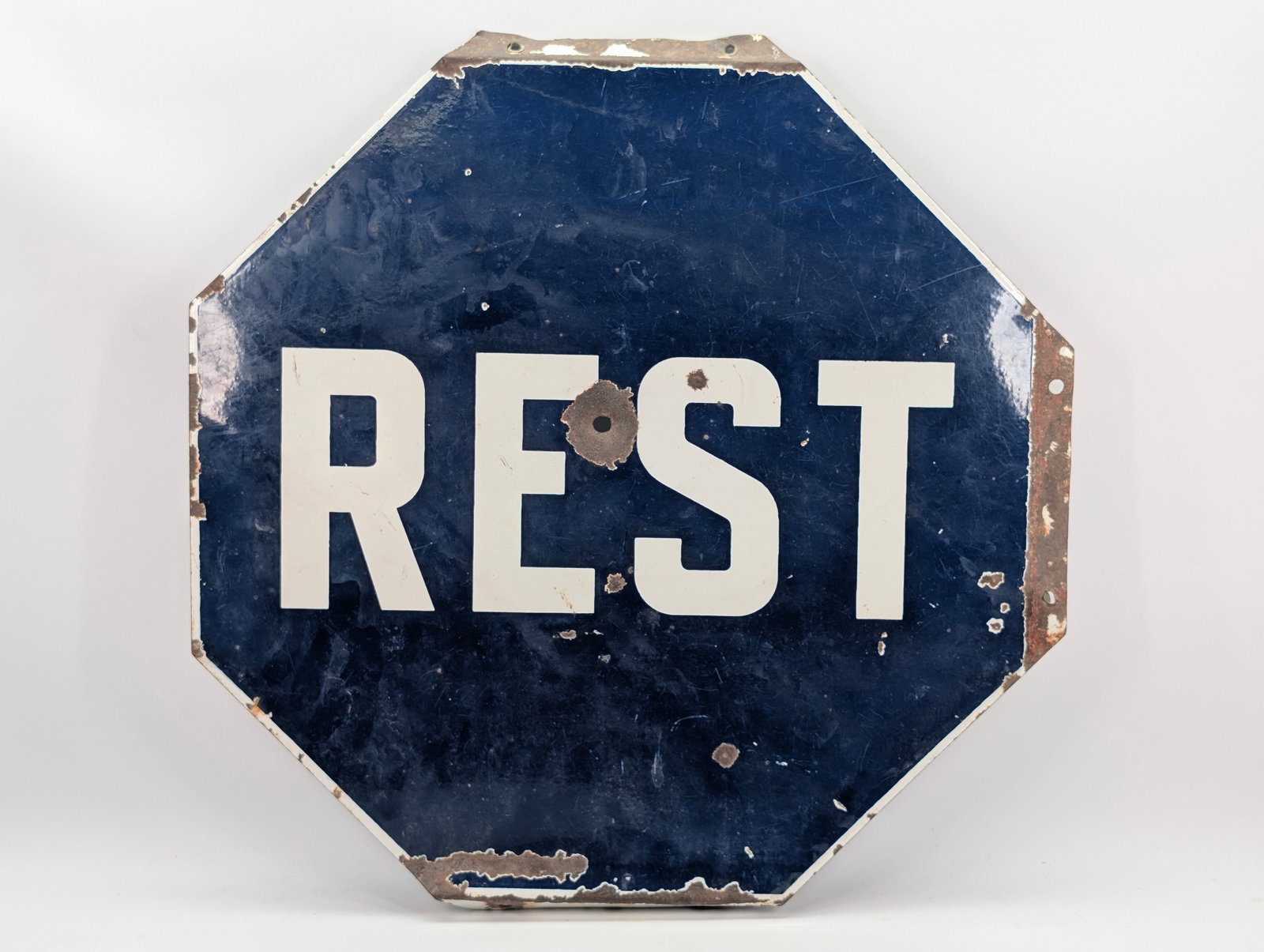 ANTIQUE PORCELAIN REST SIGN - BULLET HOLE: REMAINS IN FAIR CONDITION, SHOWING WEAR THROUGHOUT. BULLET HOLE TO CENTER AND CHIPS TO PORCELAIN ALONG FLANGED EDGES.
