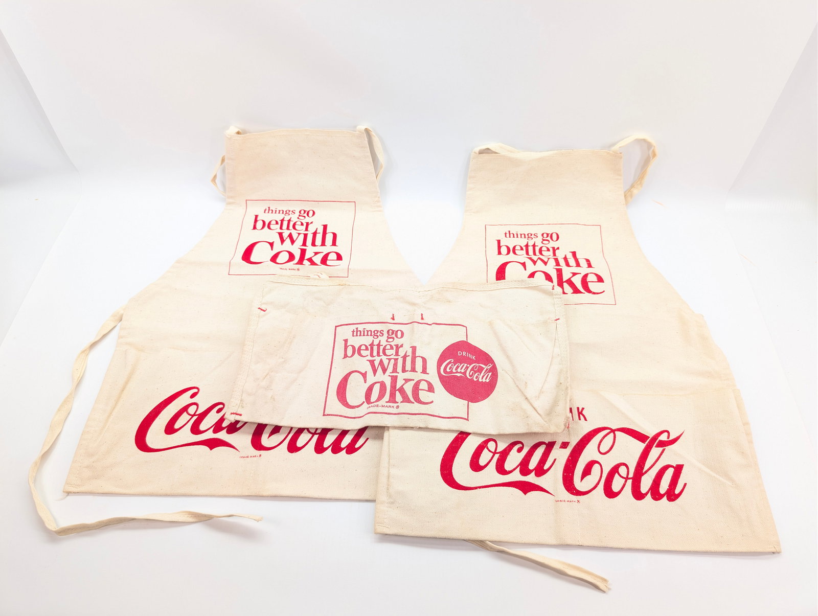 3) VINTAGE COCA COLA APRONS: ALL REMAIN IN GOOD CONDITION, SHOWING SOME WEAR.