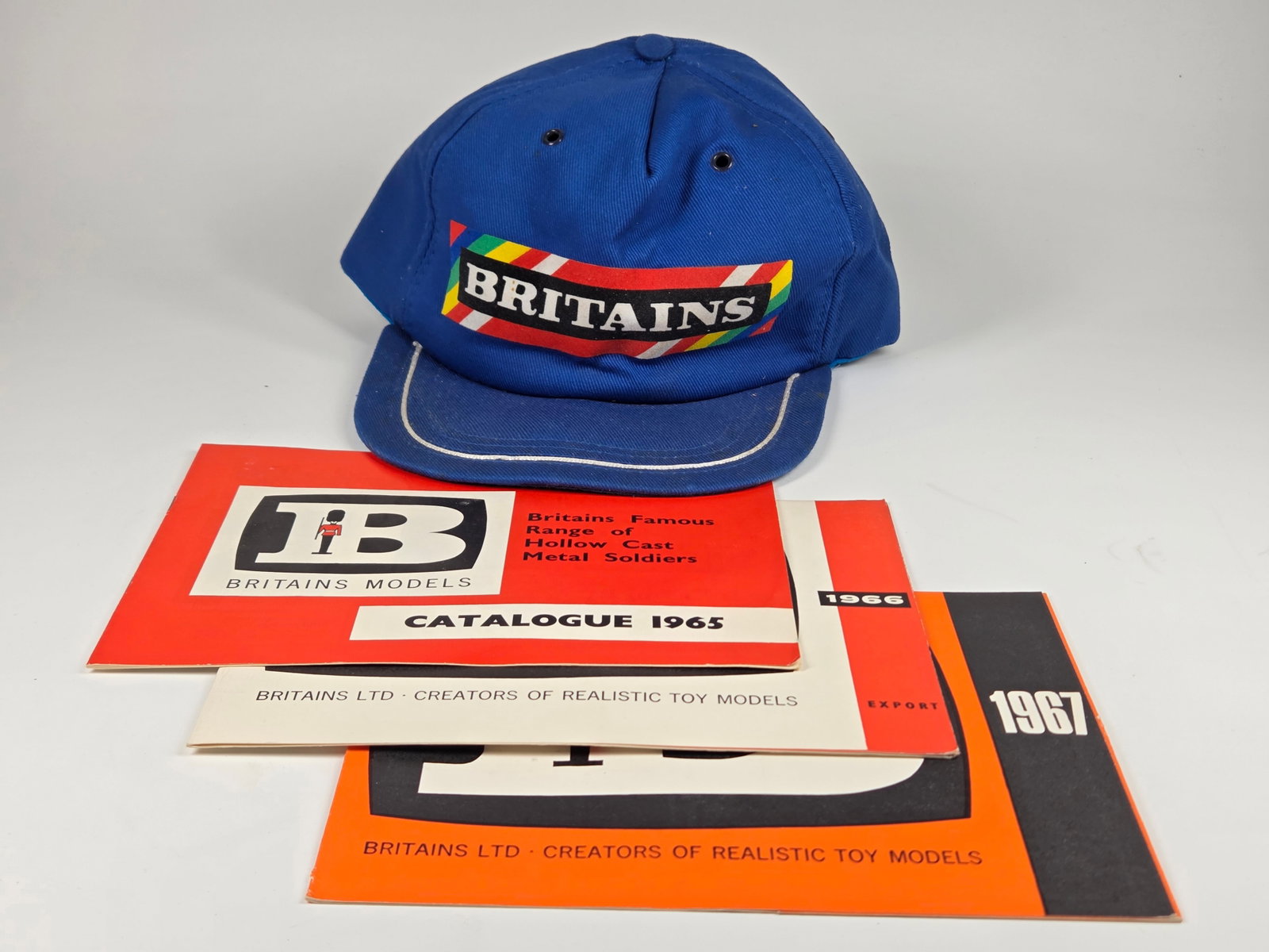BRITAINS LOGO CAP HAT & 1960'S CATALOGS: GROUP REMAINS IN VERY GOOD CONDITION