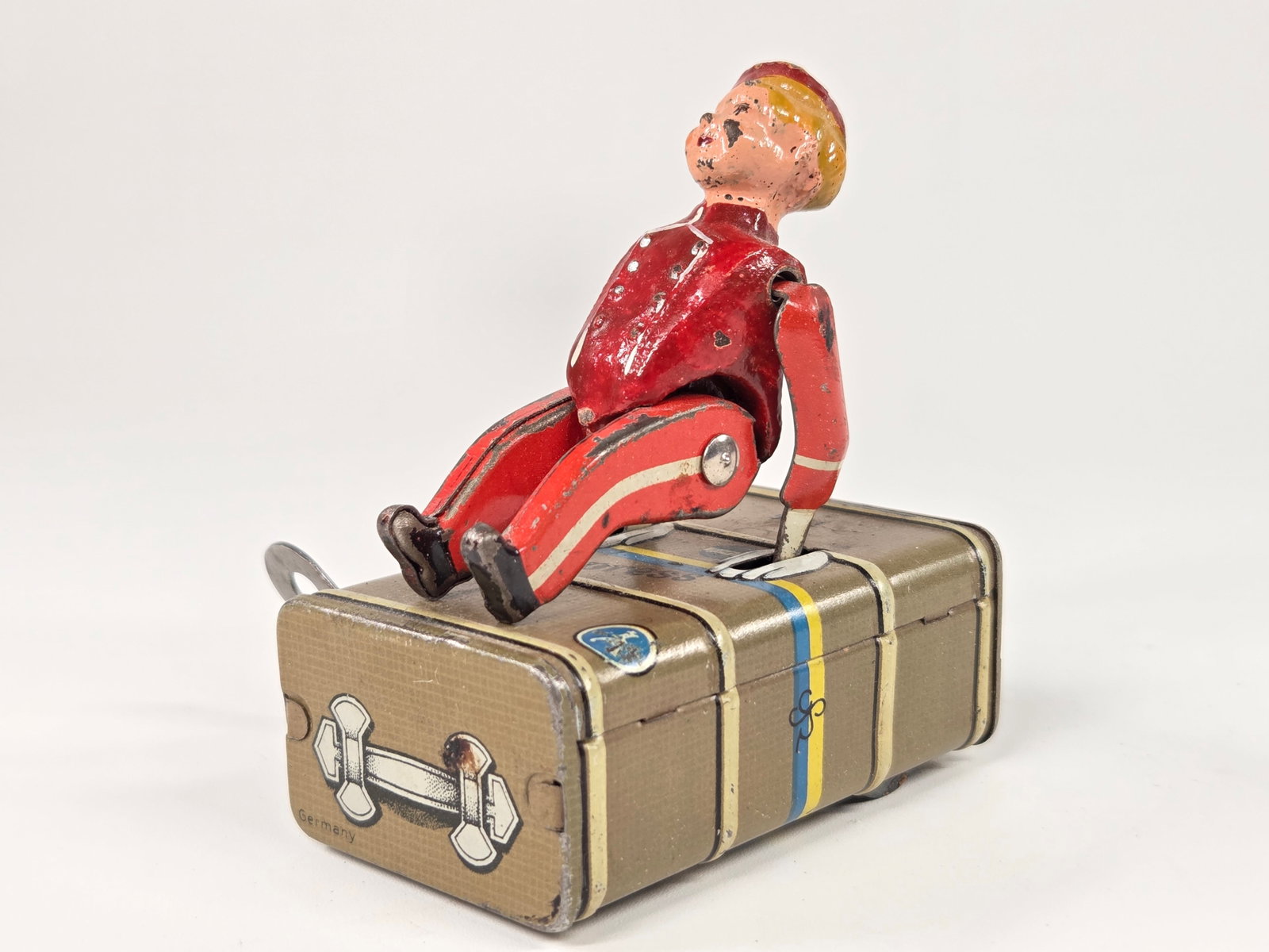 GERMAN GESCHA COMPOSITION AND TIN LITHO WIND UP LUGGAGE BOY: REMAINS IN FAIR TO GOOD CONDITION, SHOWING SOME PAINT WEAR. WIND UP MECHANISM DOES NOT WORK.