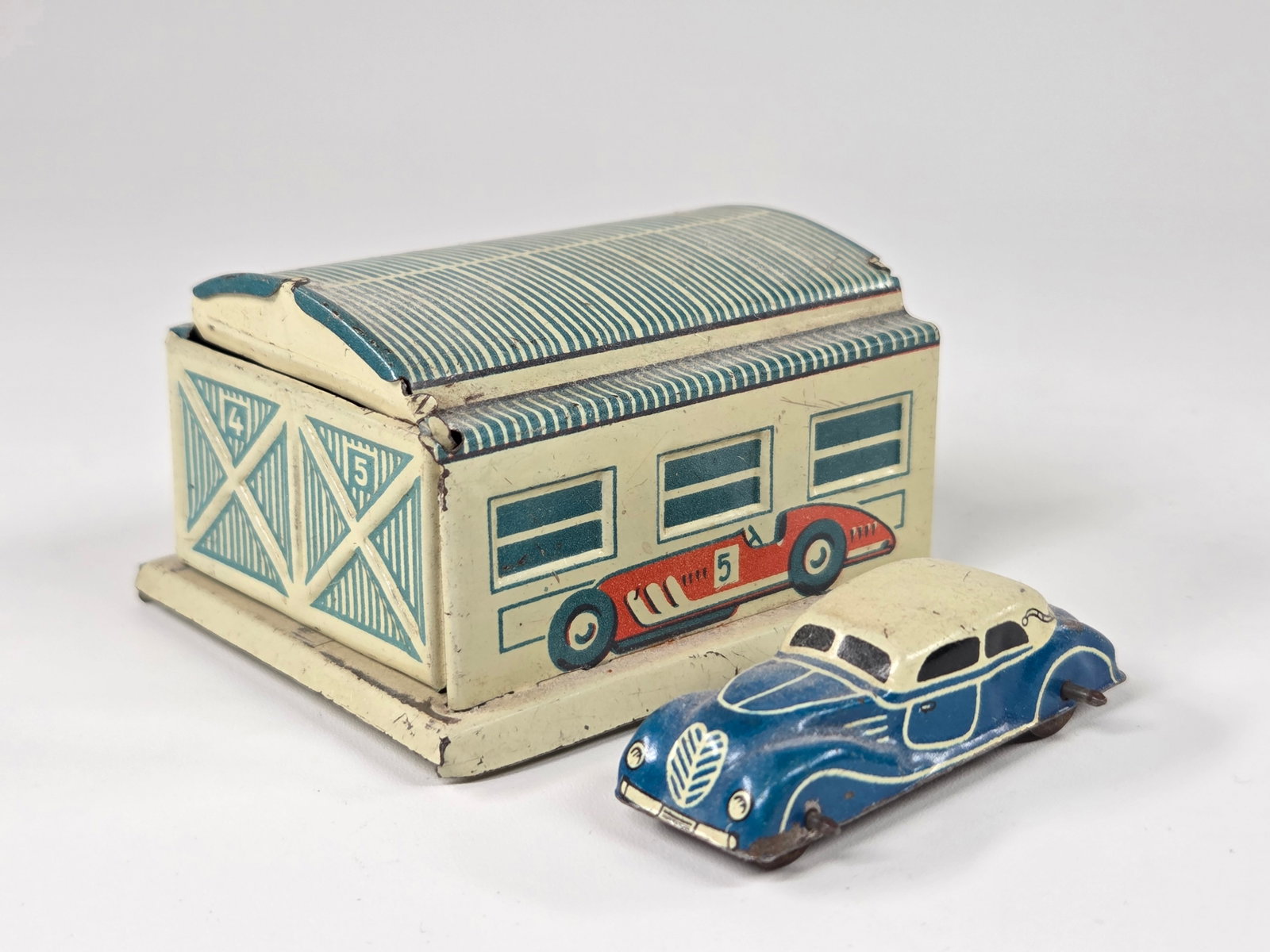 GERMAN TIN LITHO GARAGE W/ CAR - CREAM & BLUE: REMAINS IN GOOD CONDITION, SHOWING SOME TYPICAL WEAR.