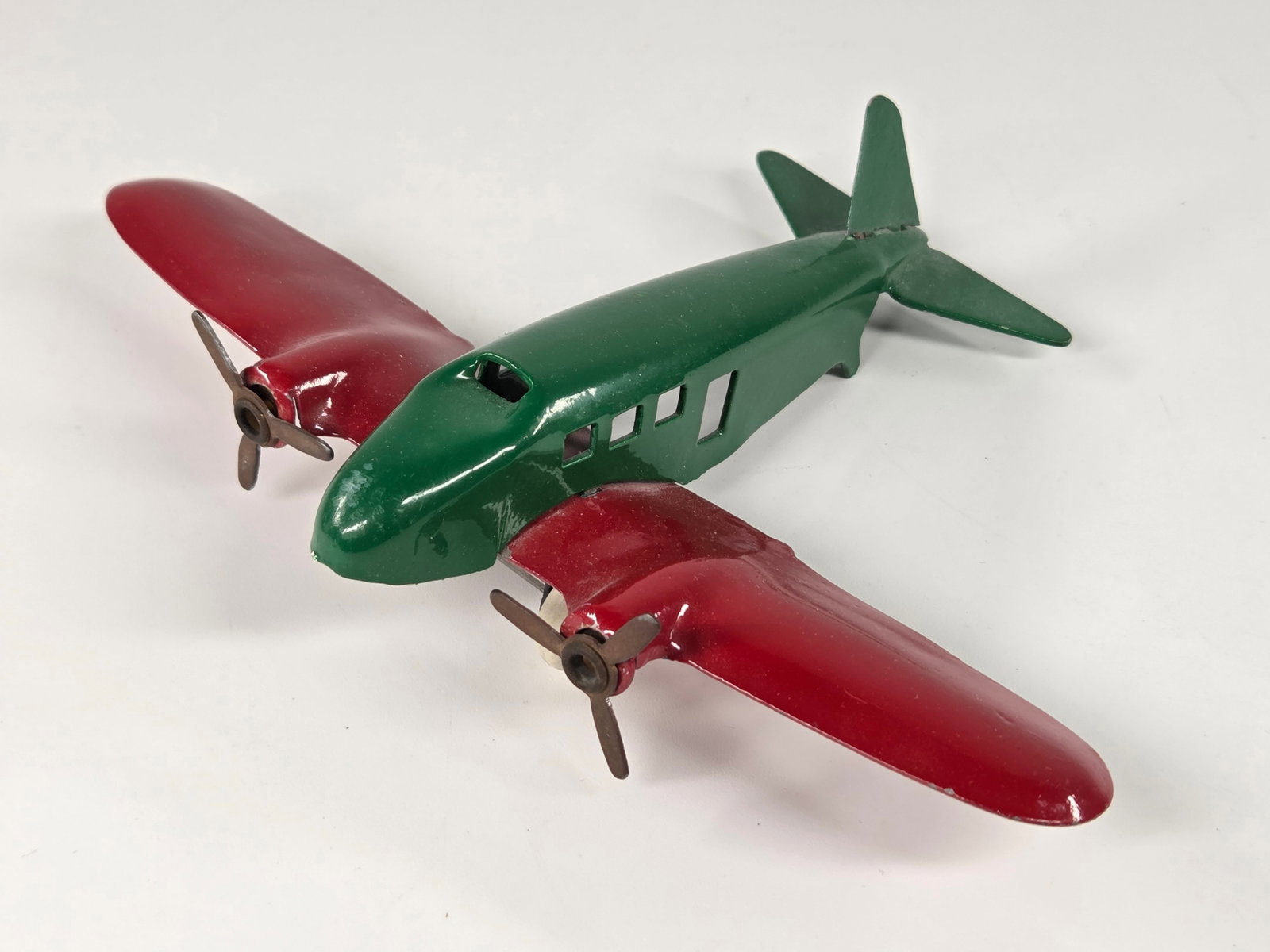 RESTORED GREEN & RED PRESSED STEEL AIRPLANE: REMAINS IN GOOD CONDITION, SHOWING SOME LIGHT TYPICAL WEAR.