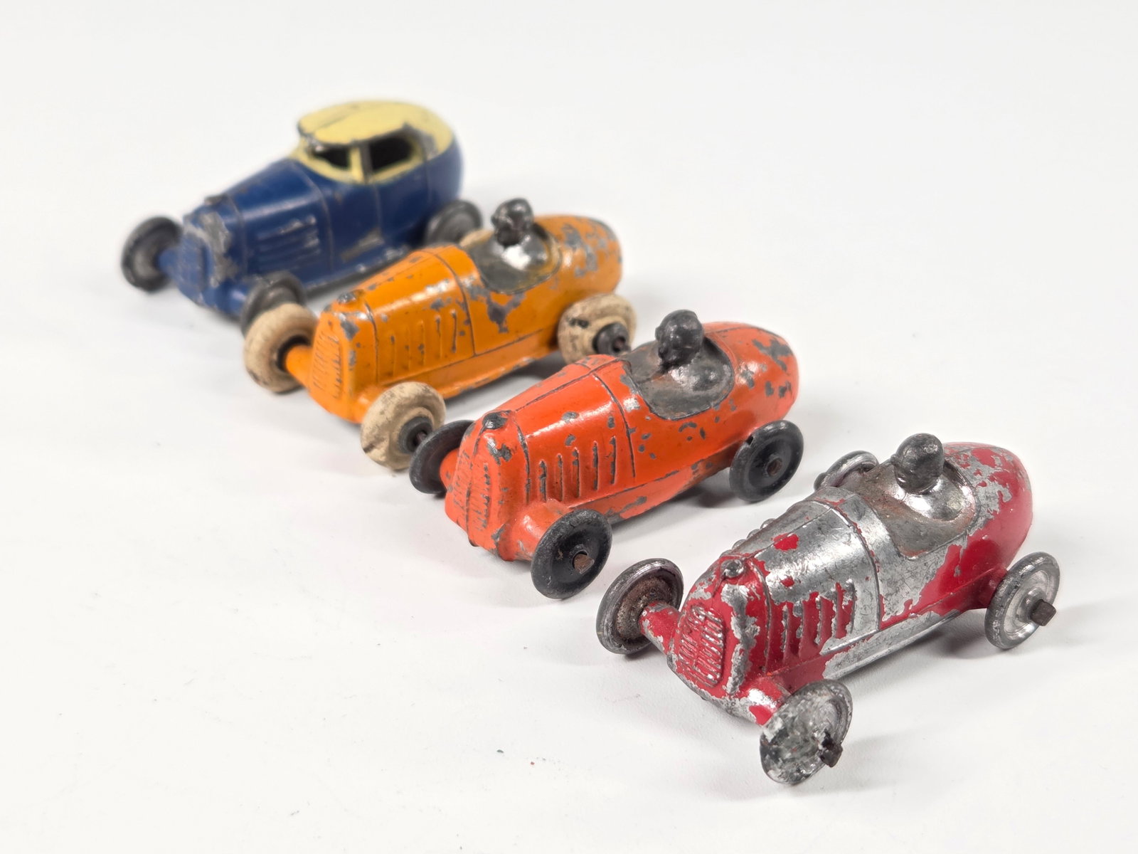 4) ANTIQUE SLUSH METAL RACE CARS: ALL REMAIN IN FAIR TO GOOD CONDITION, SHOWING PAINT WEAR.