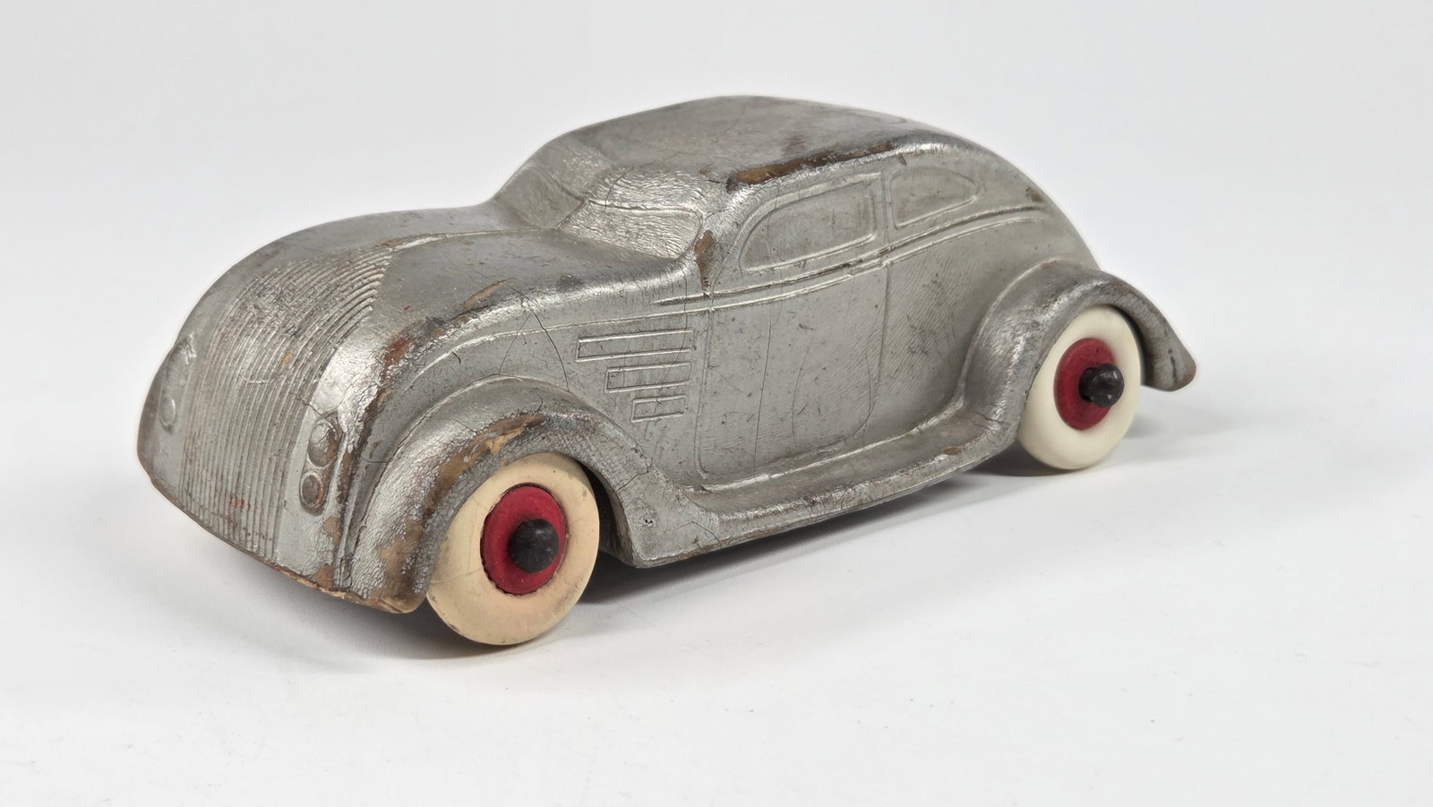 VINTAGE HEAVY RUBBER CHRYSLER AIRFLOW: REMAINS IN FAIR TO GOOD CONDITION, SHOWING SOME TYPICAL WEAR. A FEW LIGHT CRACKS. PAINT RUBS. TWHEELS REPLACED.