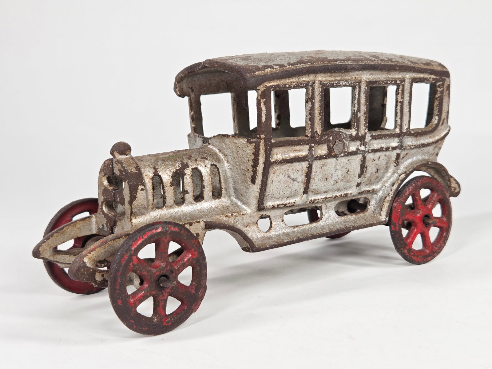 ANTIQUE CAST IRON SEDAN W/ RED SPOKE WHEELS: REMAINS IN FAIR CONDITION, SHOWING PAINT WEAR.