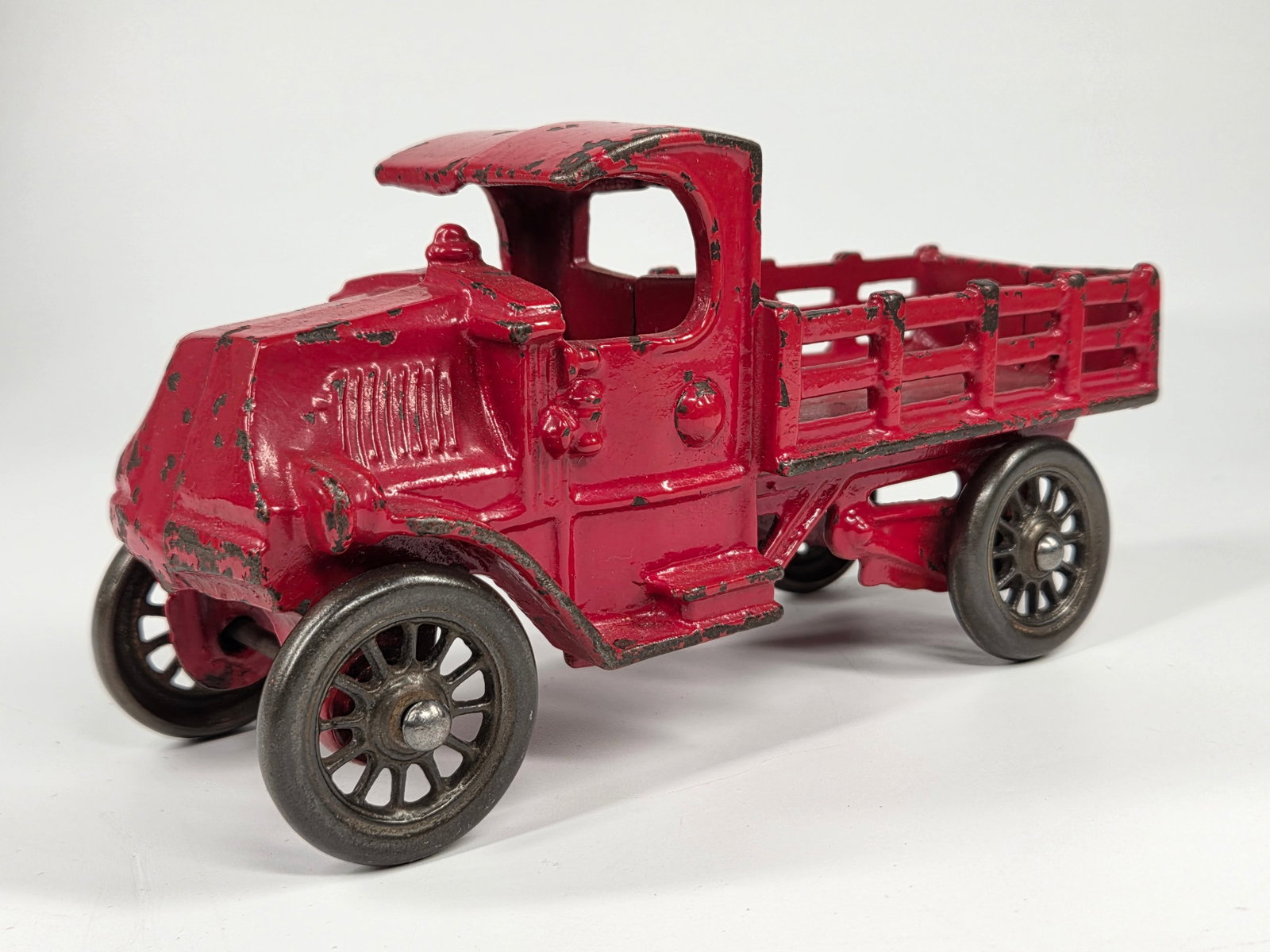 CAST IRON MACK CAB STAKE BODY TRUCK: REMAINS IN GOOD CONDITION, SHOWING PAINT WEAR.