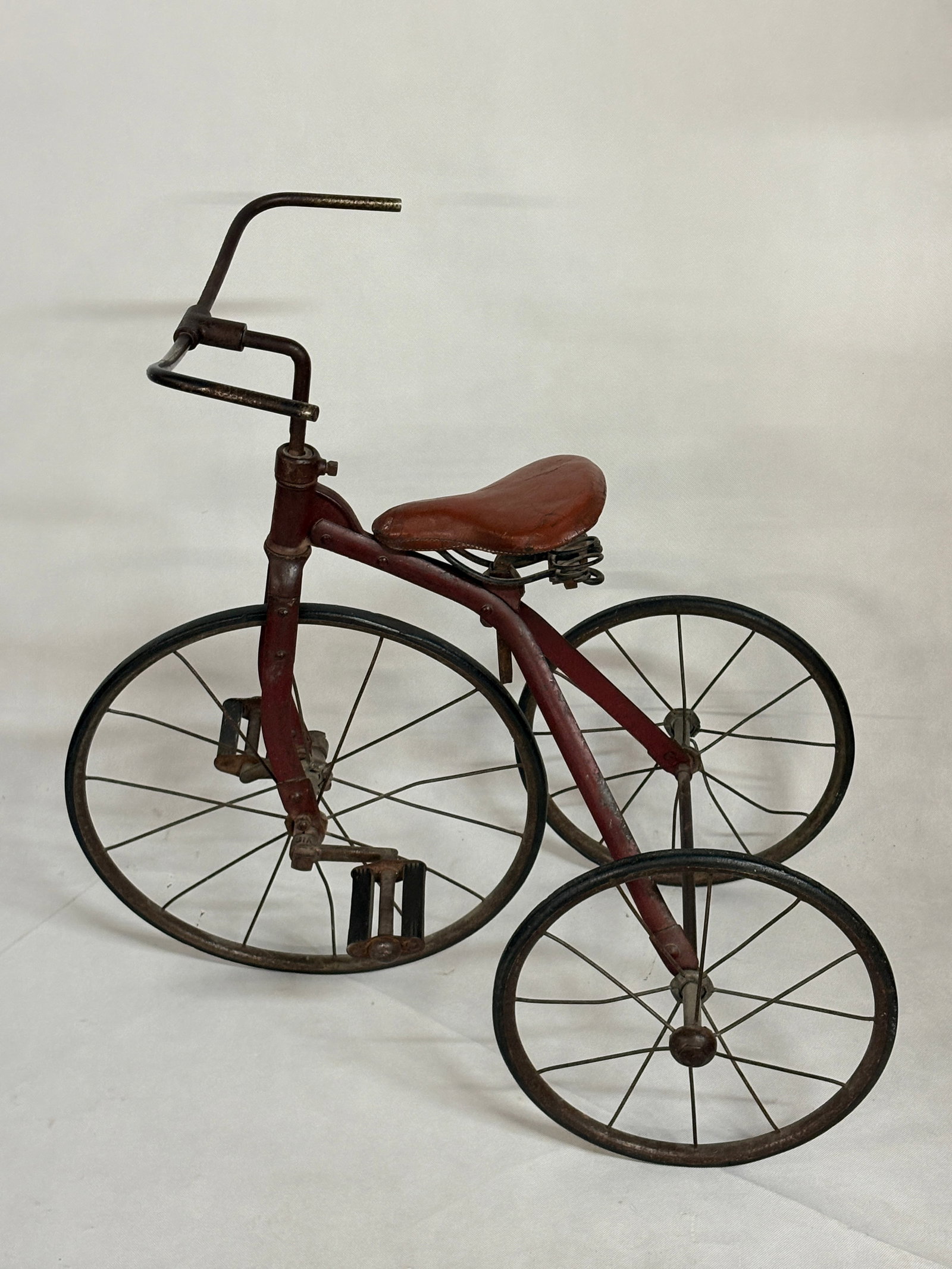 ANTIQUE CHILD'S TRICYCLE W/ LEATHER SEAT: REMAINS IN GOOD CONDITION, SHOWING SOME TYPICAL WEAR. PAINTED RED. APPEARS TO BE ORIGINAL SEAT. SEAT REMAINS NICE.
