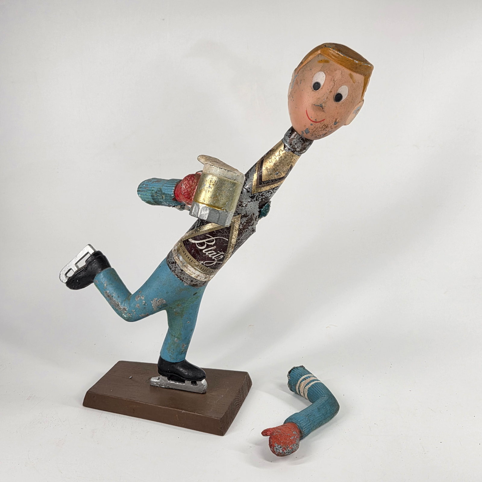 VINTAGE BLATZ BEER ICE SKATER FIGURAL BEER PROMO STATUE: REMAINS IN FAIR CONDITION WITH PAINT LOSS, ARM SEPARATION - GENERAL WEAR. WOOD BASE