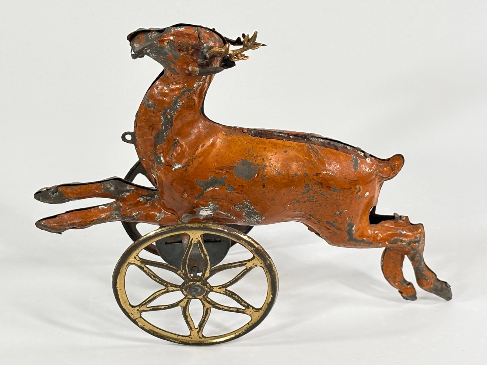 ANTIQUE GERMAN PAINTED TIN REINDEER PULL TOY: REMAINS IN FAIR CONDITION, SHOWING SOME PAINT WEAR. APPEARS TO HAVE ANTLERS REPLACED.