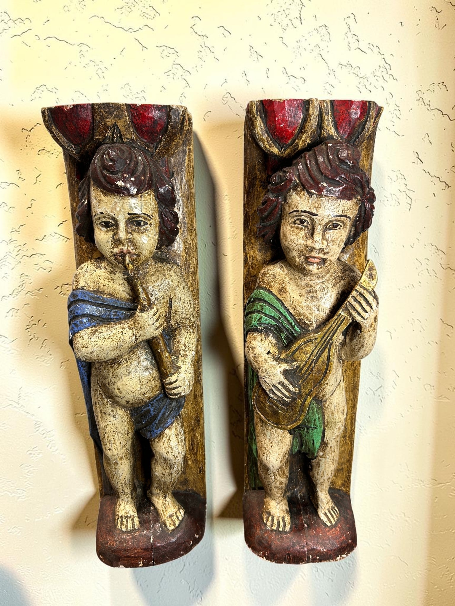 Pair of Late 17th Century Antique Wooden Polychrome Musical Cherub Caryatid Wall Sculptures: This remarkable pair of Late 17th Century antique wooden polychrome musical cherub caryatid wall sculptures features beautifully hand-carved putti figures rendered with expressive detail and old-world