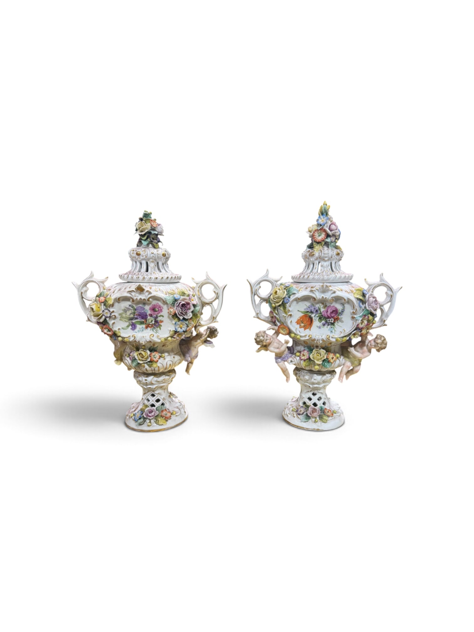 Pair of Antique Capodimonte Porcelain Cherub Urns with Applied Floral Decoration: An exquisite pair of antique Capodimonte porcelain urns featuring elaborate applied floral decoration, hand-painted floral reserves, and sculptural cherub figures in the Rococo Revival style. These hi