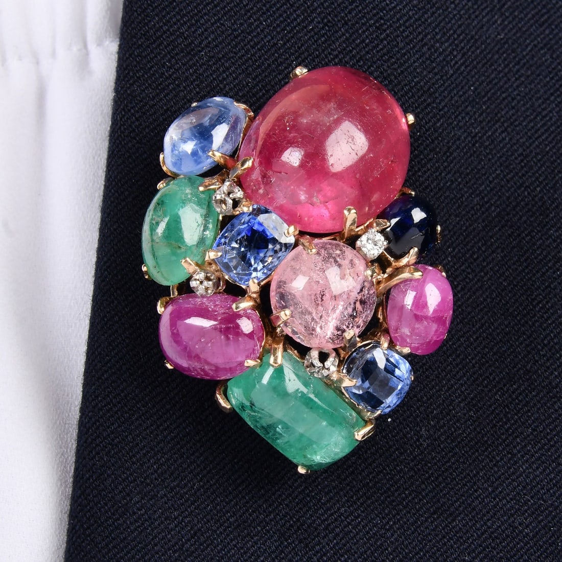 Vintage Seaman Schepps Emerald Ruby Sapphire Tourmaline 65.50ct Diamond 18K Gold Brooch 22.4 Grams: A stunning vintage brooch by Seaman Schepps, crafted in rich 18K yellow gold and adorned with a vibrant cluster of natural gemstones. This bold, one-of-a-kind statement piece showcases a dazzling arra