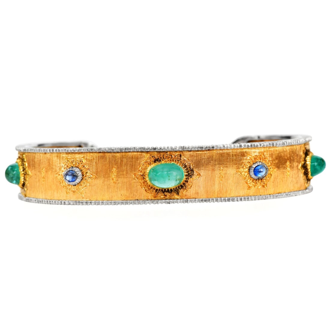 Mario Buccellati Vintage Emerald Sapphire 18K Yellow White Gold Cuff Bangle: A rare vintage cuff bracelet by Mario Buccellati, crafted in 18K yellow gold with white gold accents and the house?s signature hand-engraved rigato and tulle detailing. The wide cuff is adorned with c