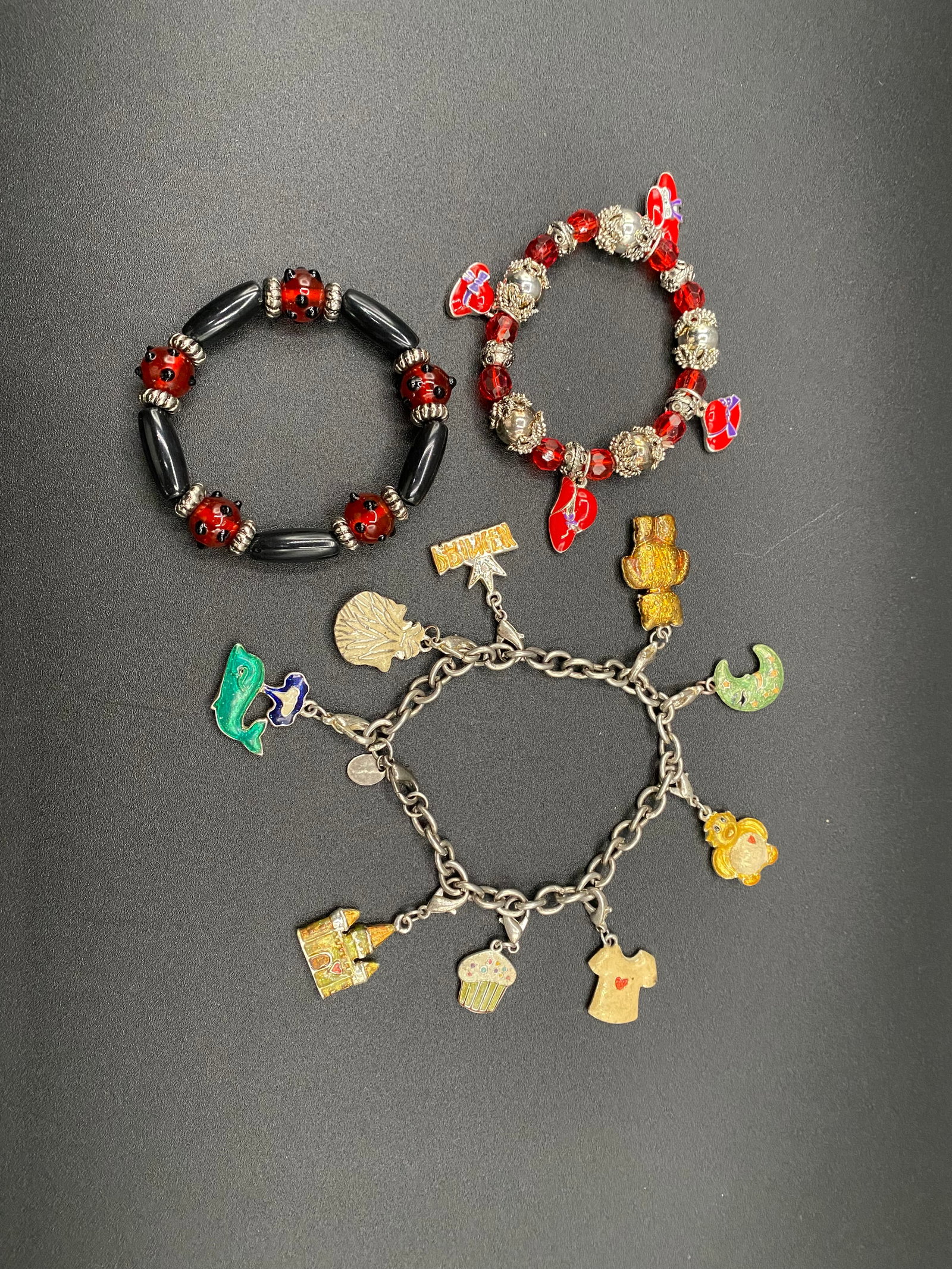 Vintage Charm Bracelet & Beaded Stretch Set – Ladybug Accents & Multi-Charm Silver-Tone Bracelet: A charming three-piece collection of vintage bracelets featuring playful motifs and vibrant red accents. This lot includes:• Silver-Tone Multi-Charm Bracelet: A classic link chain featuring a var