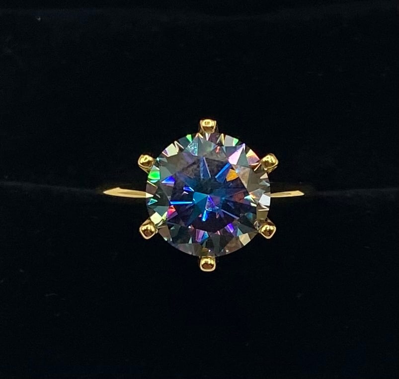 5.00ct Round Brilliant Moissanite Triple-Band Statement Ring: This striking statement ring features a magnificent 5.00-carat round brilliant cut moissanite center stone. Known for its exceptional fire and "rainbow" scintillation, this moissanite passes as a