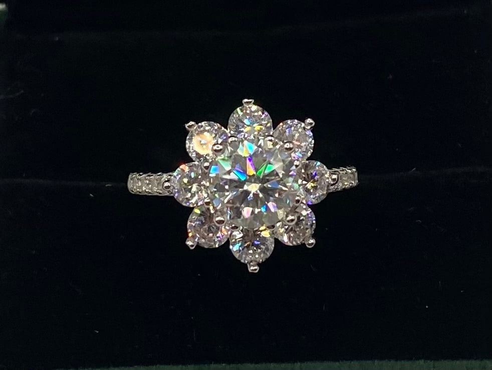 Moissanite Floral Cluster Halo Ring - 18k White Gold Finish: A breathtaking floral-inspired "Sunflower" design. This ring features a large round brilliant Moissanite center surrounded by a petal-like halo of smaller round Moissanites, totaling 2 carats. The