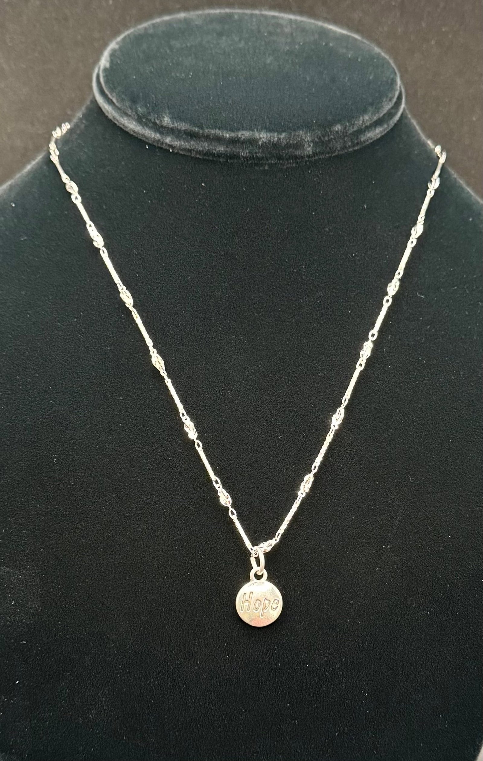 Vintage Sterling Silver Hope Script Circular Charm & Bar Link Chain Necklace: This elegant sterling silver necklace features a minimalist circular charm embossed with the word "Hope" in a stylized script. The charm is suspended from a delicate yet distinctive bar-and-eyelet lin
