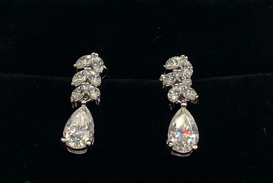 Pear & Marquise Cut Moissanite Drop Earrings 18K GP Silver: Gemstone Type: Authentic Moissanite Stone Cut/Shape: Elegant Pear Cut drops suspended from a cluster of Marquise Cut accents. Stone Color: Brilliant Clear (D-E-F Colorless range) Metal Composition: