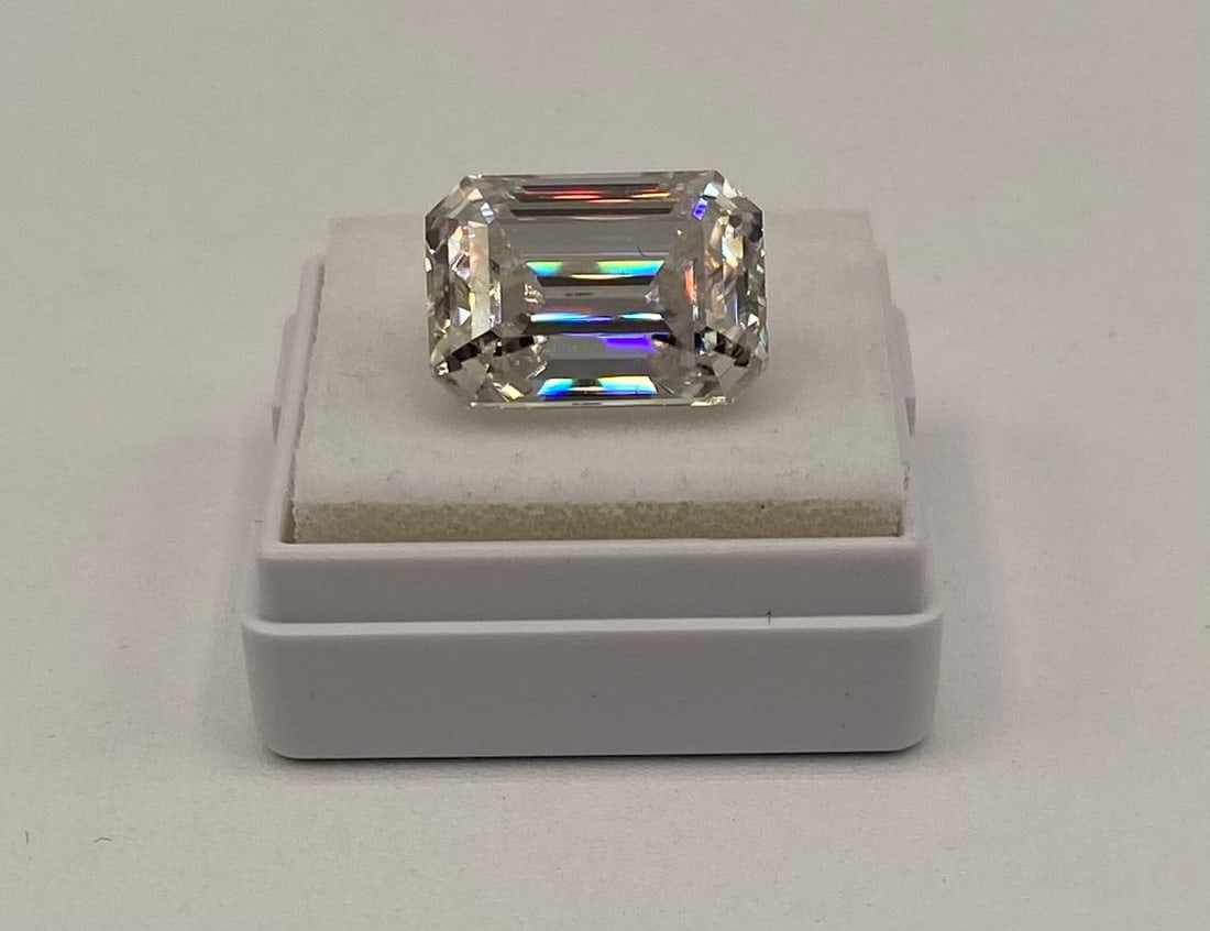 10 Ct Emerald Step Cut Moissanite VVS Loose Gemstone w/ Cert: One loose, emerald step cut moissanite gemstone. Carat Weight: 10.00 Carats Clarity: VVS Certification: Includes certificate of authenticity. Testing: Positively tests as diamond using standard therma