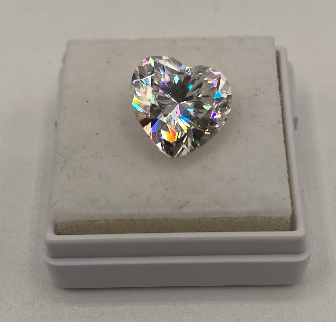 5 Ct Heart Modified Brilliant Cut Moissanite VVS Loose Gemstone w/ Cert: One loose, heart-shaped modified brilliant cut moissanite gemstone. Carat Weight: 5 Carats Clarity: VVS Certification: Includes certificate of authenticity. Testing: Positively tests as diamond using