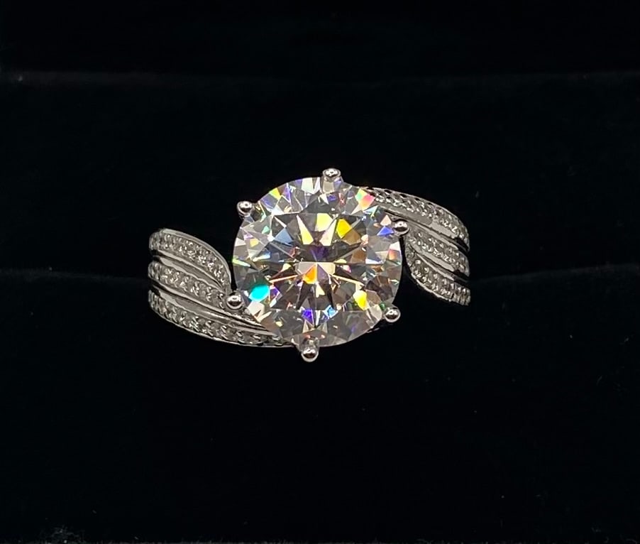 5 CT VVS Moissanite Bypass Ring, 18K White Gold Plated: Center Stone: Moissanite Carat Weight: 5.00 Carats Clarity: VVS Metal: 18K White Gold Plated over Sterling Silver Ring Size: 9 Testing: Confirmed to pass as diamond on standard thermal diamond