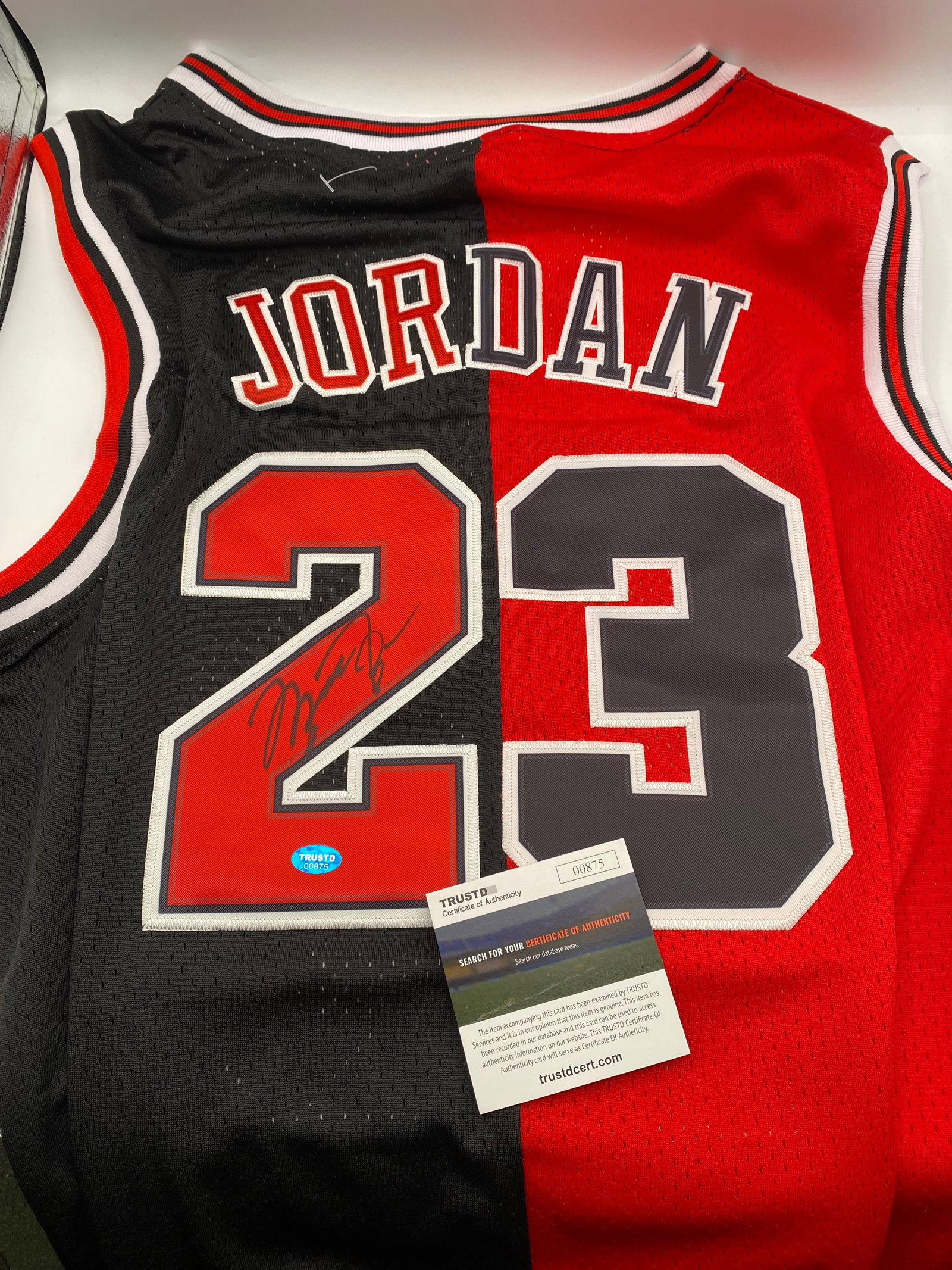 Michael Jordan Signed Chicago Bulls Split Jersey (TRUSTD COA): A unique collector's piece featuring a black and red split-design Chicago Bulls jersey hand-signed by the legendary Michael Jordan. The distinct autograph is signed on the red portion of the iconic