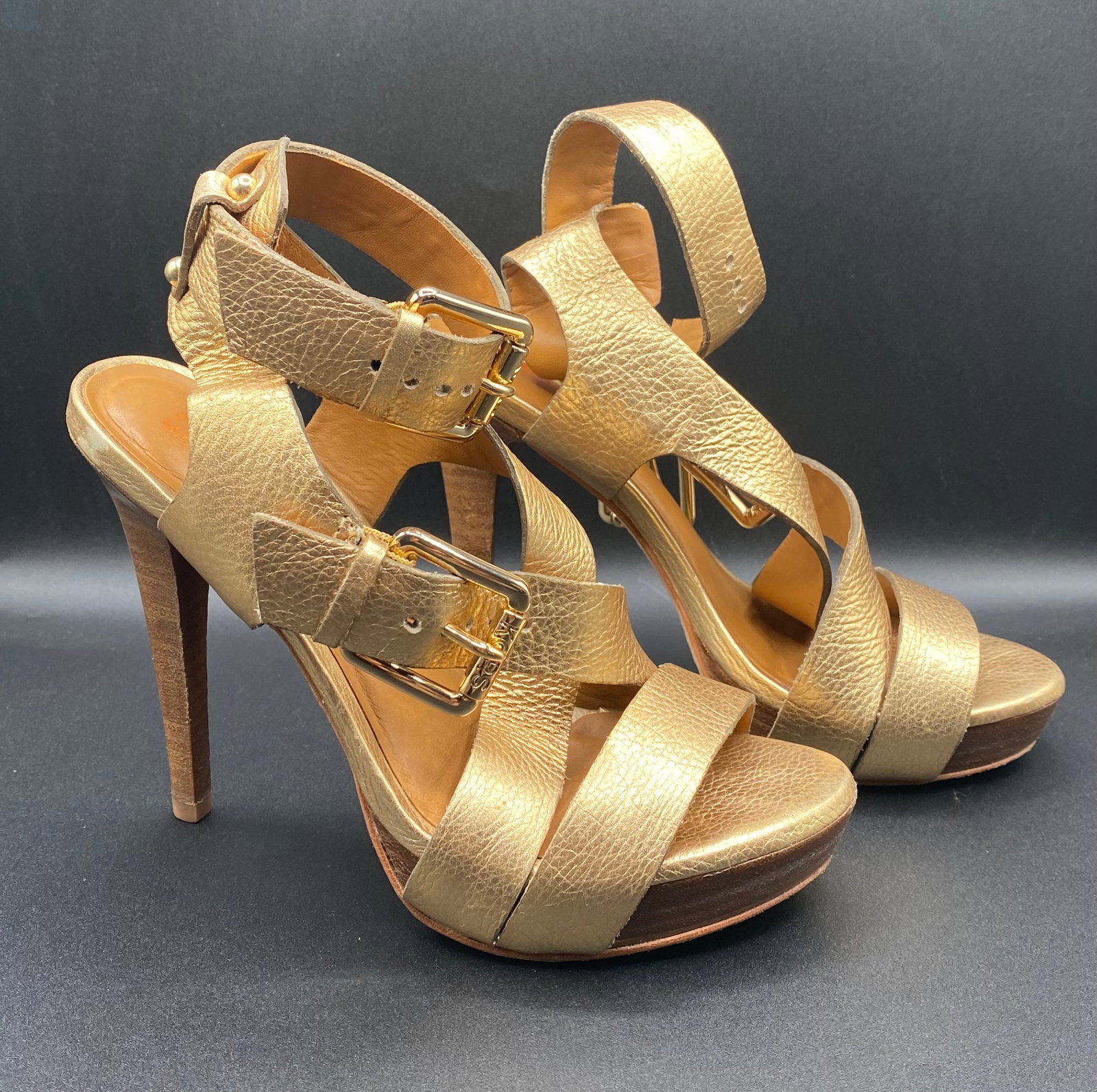 KORS Michael Kors Gold Metallic Leather Strappy Buckle Platform Heels: Up for auction is a statement pair of KORS Michael Kors Strappy Platform Heels in a metallic gold pebbled leather finish. Designed with caged buckled ankle straps, polished gold-tone hardware, high st