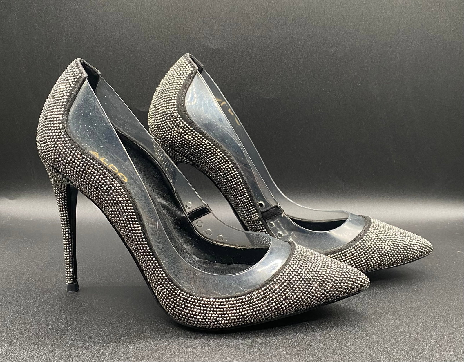 Aldo "Shieryl" Rhinestone & Clear PVC Pointed-Toe Stiletto Pumps: Up for auction is a showstopping pair of Aldo "Shieryl" Stiletto Pumps adorned with allover gunmetal/pewter rhinestones and clear PVC side panels. Designed with sharp pointed toes, classic d'Orsay tra