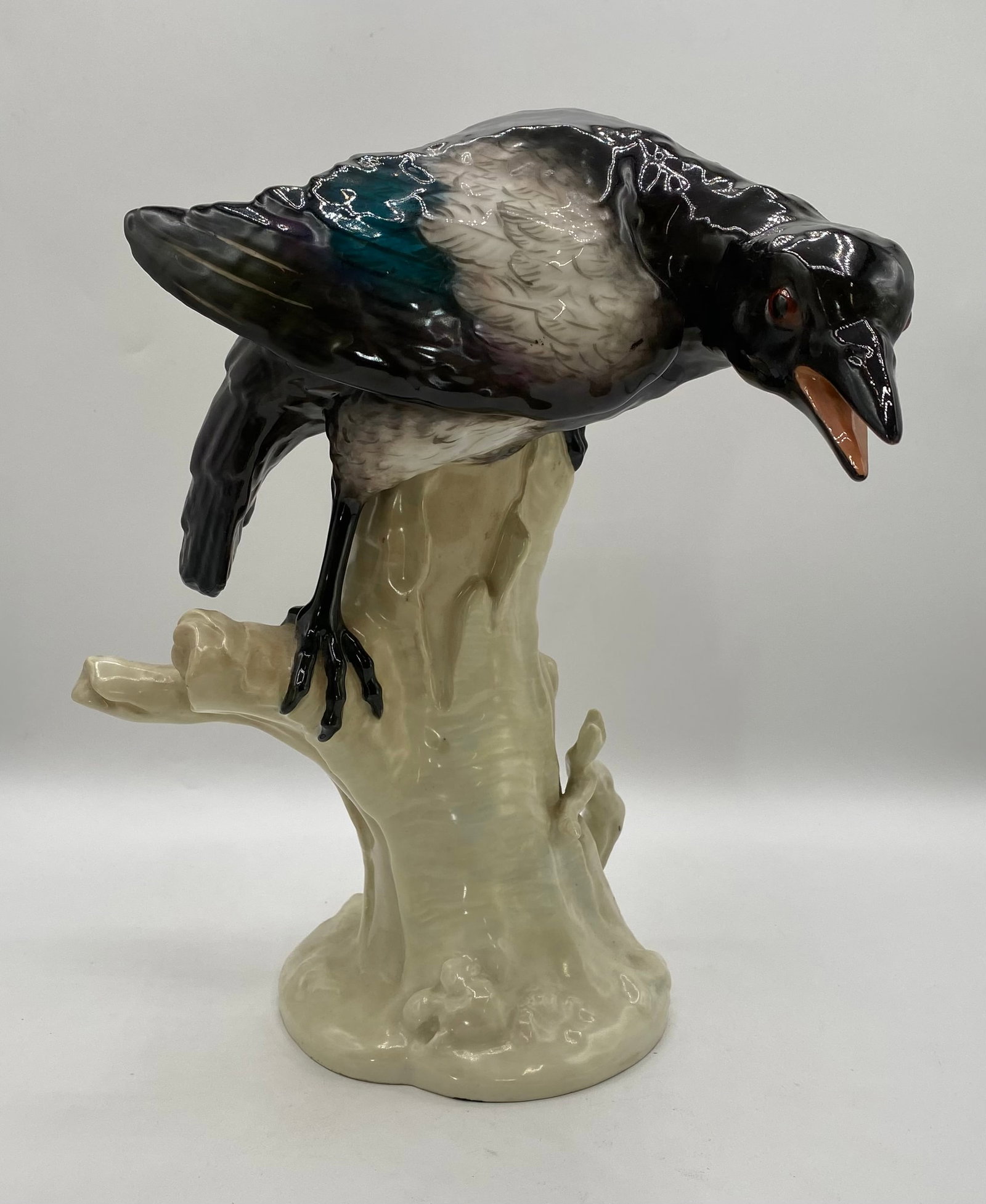 Antique KPM Royal Berlin Porcelain Magpie Bird Figurine on Tree Trunk: A finely detailed antique German hand-painted porcelain figurine depicting a magpie perched forward atop a tree trunk branch with an open beak. Manufacturer: KPM (Königliche Porzellan-Manufaktur Berl