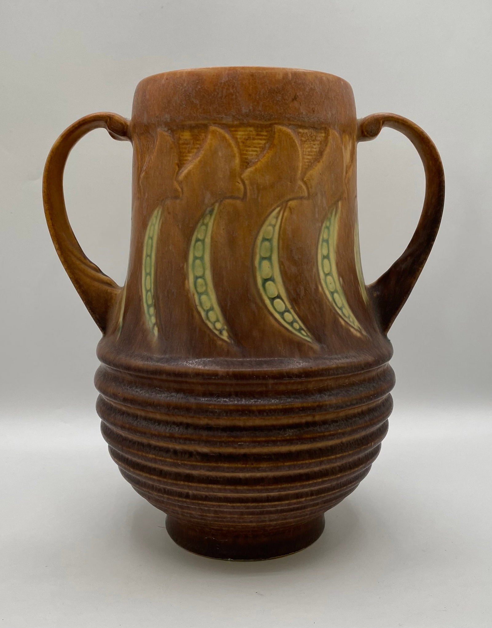 1933 Roseville Pottery Falline Two-Handled Vase: An authentic 1933 Roseville Pottery two-handled vase in the desirable "Falline" line. The piece features a brown and tan ground with stylized green embossed pea pod/botanical motifs around the neck