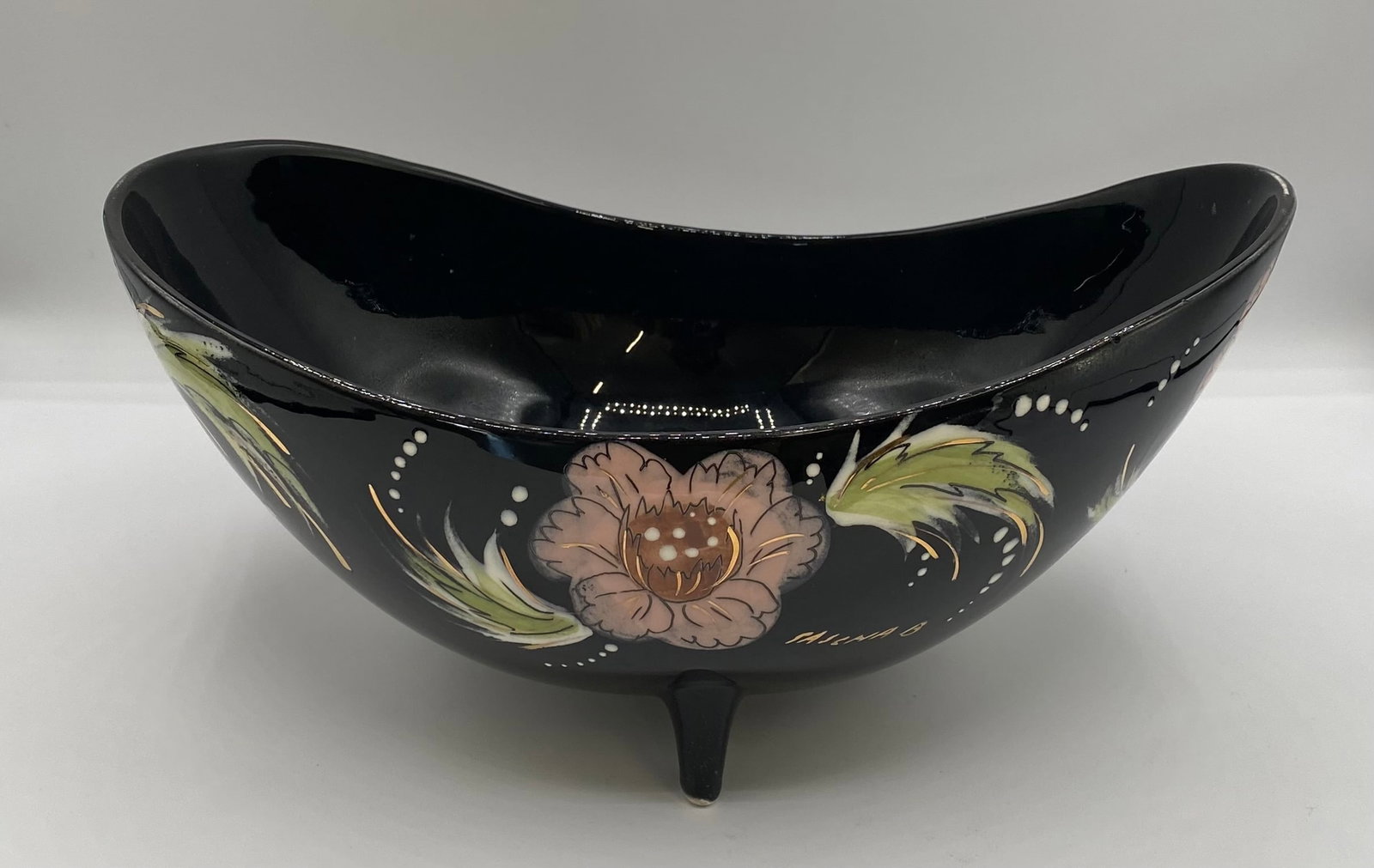 Mid-Century Modern Sascha Brastoff Floral Footed Boat Bowl - Black & Gold: An elegant 1950s California art pottery boat-shaped footed bowl designed by Sascha Brastoff, featuring hand-painted muted pink flowers, green foliage, and white accents with fine metallic gold details