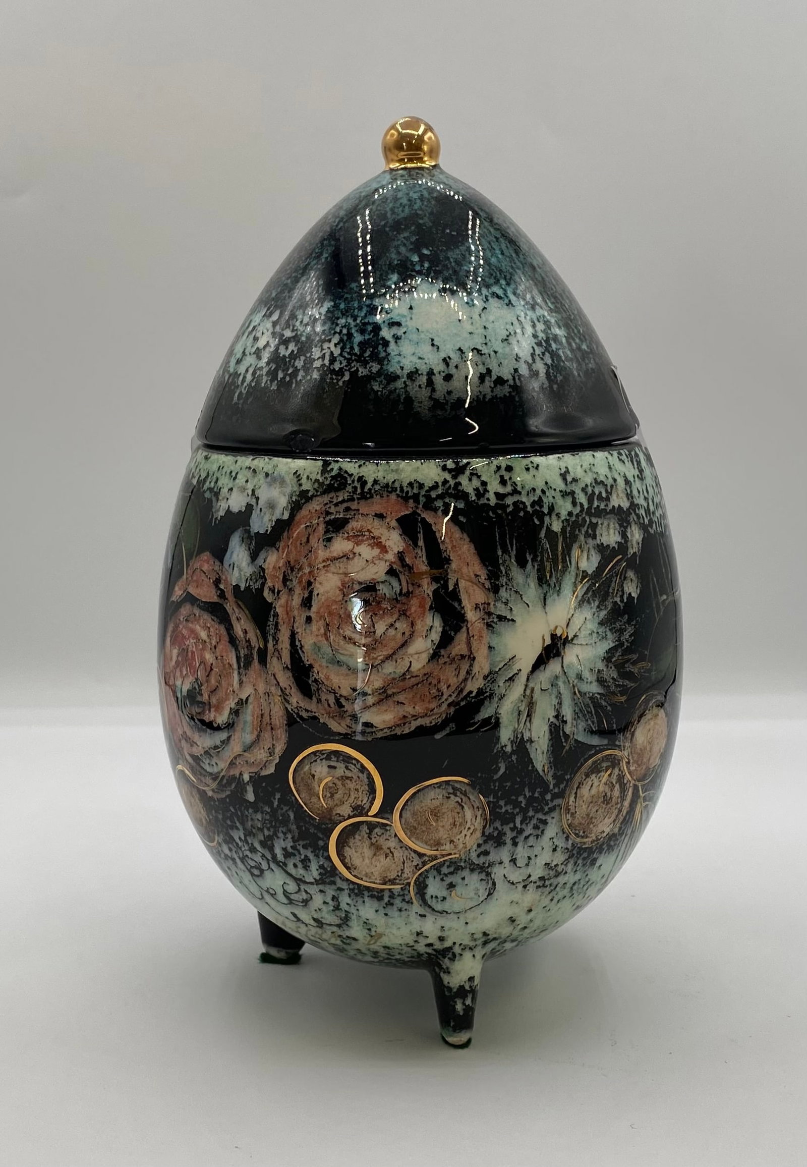 Sascha Brastoff Floral Lidded Egg Jar on Feet - 8": An unusual Mid-Century Modern California art pottery egg-shaped lidded jar by Sascha Brastoff, featuring a hand-painted floral motif in soft pink and ivory tones with metallic gold leaf accents over a