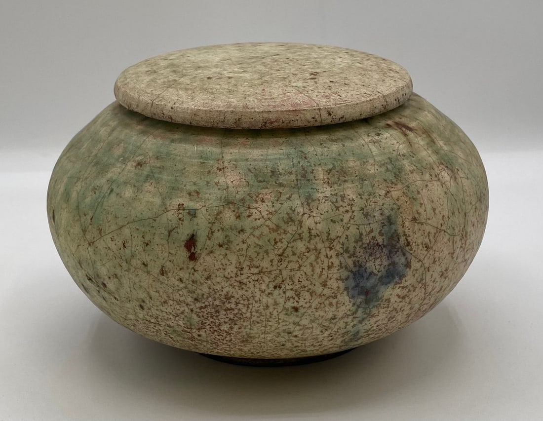 Mike Brennan Studio Art Pottery Covered Raku Ginger Jar: Up for auction is a hand-thrown studio art pottery covered Raku jar by Laguna Beach, California artist Mike Brennan. The bulbous pot features a subtle green, earth-tone, and copper-flashed crackle gla