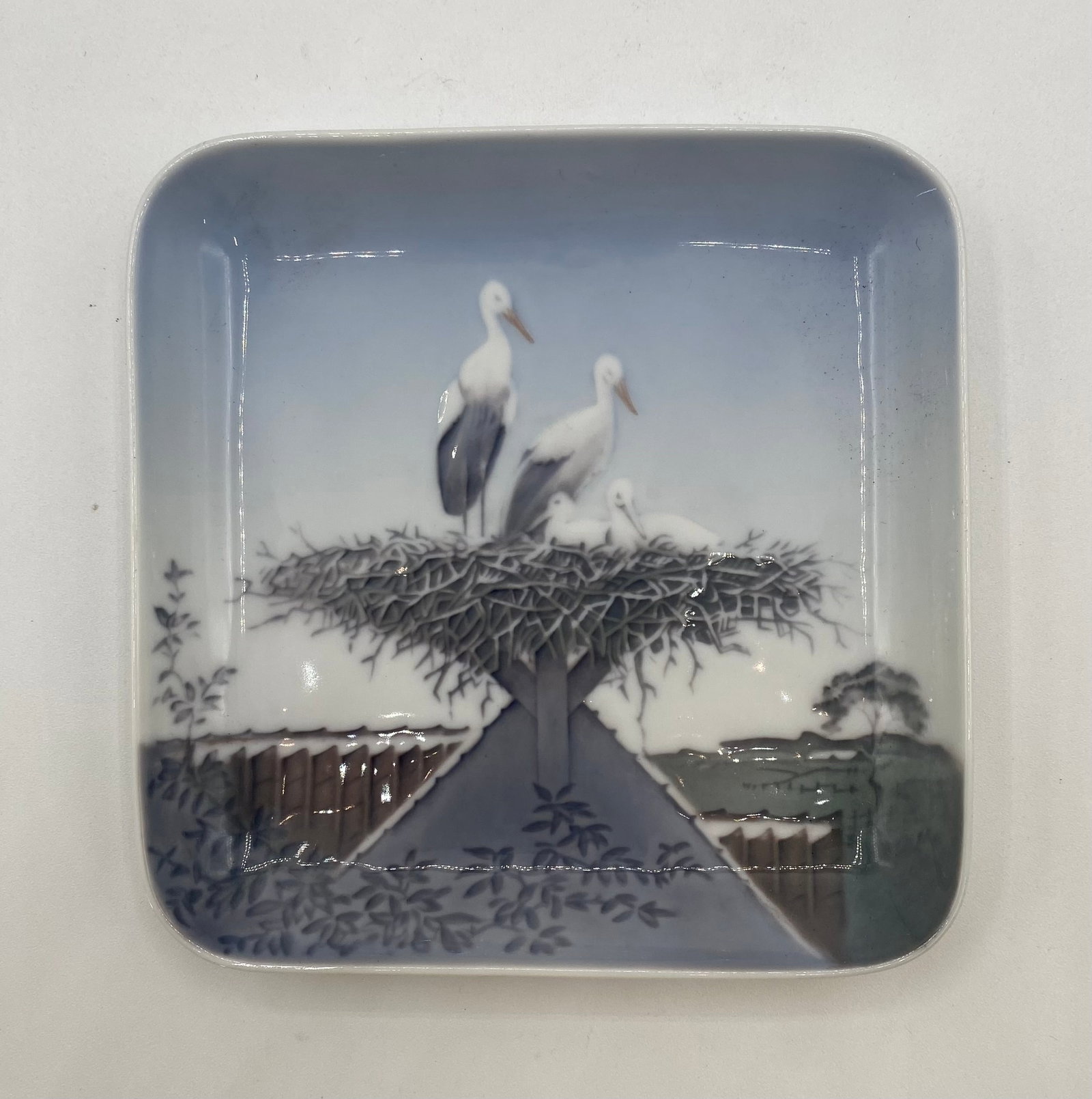 Vintage Bing & Grøndahl Danish Porcelain Storks Nest Dish #583/455: Up for auction is a vintage Bing & Grøndahl fine porcelain square dish / small wall plaque depicting a family of white storks in their nest atop a tiled rooftop, finished in soft blue and grey underg
