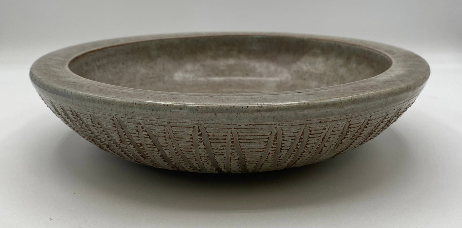 Studio Art Pottery Carved Stoneware Shallow Bowl / Dish, Silver Springs: Up for auction is a hand-thrown studio art pottery shallow bowl / dish. Features a speckled grey-tan glazed interior with a wide flat rim, while the exterior sides exhibit intricate carved/chiseled sg