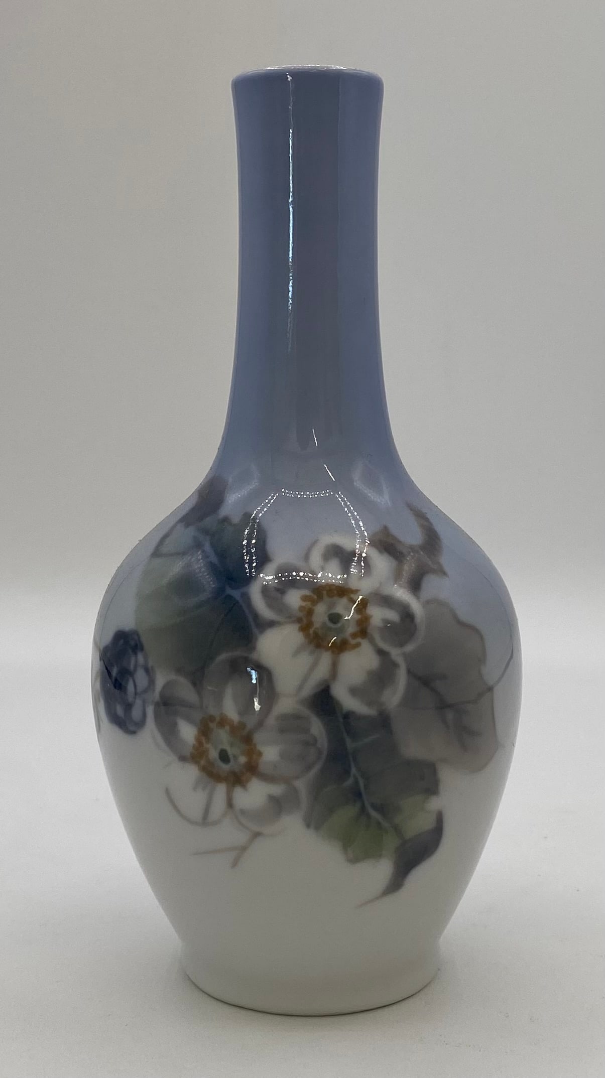 Royal Copenhagen Denmark Porcelain Floral Bud Vase #288-43A: Danish fine porcelain bud vase produced by Royal Copenhagen. Features hand-painted white blossoms with leafy botanical detailing against a soft blue and grey gradient background. Base bears the offici