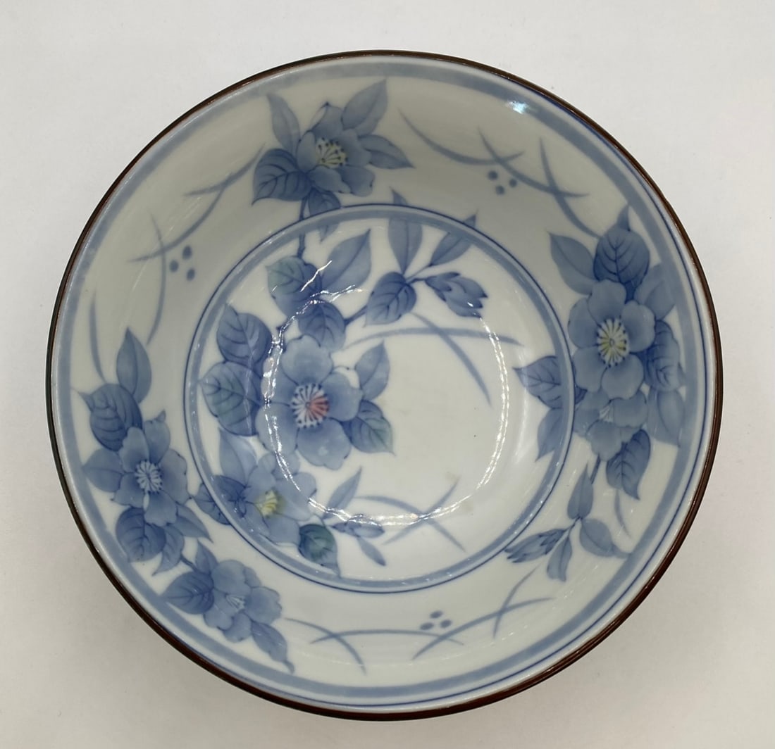 Japanese Blue & White Underglaze Floral Porcelain Bowl with Textured Exterior: A Japanese porcelain bowl decorated with underglaze blue botanical blossoms on the interior and an intricate textured/carved pattern across the exterior. Finished with a brown-trimmed rim and a square