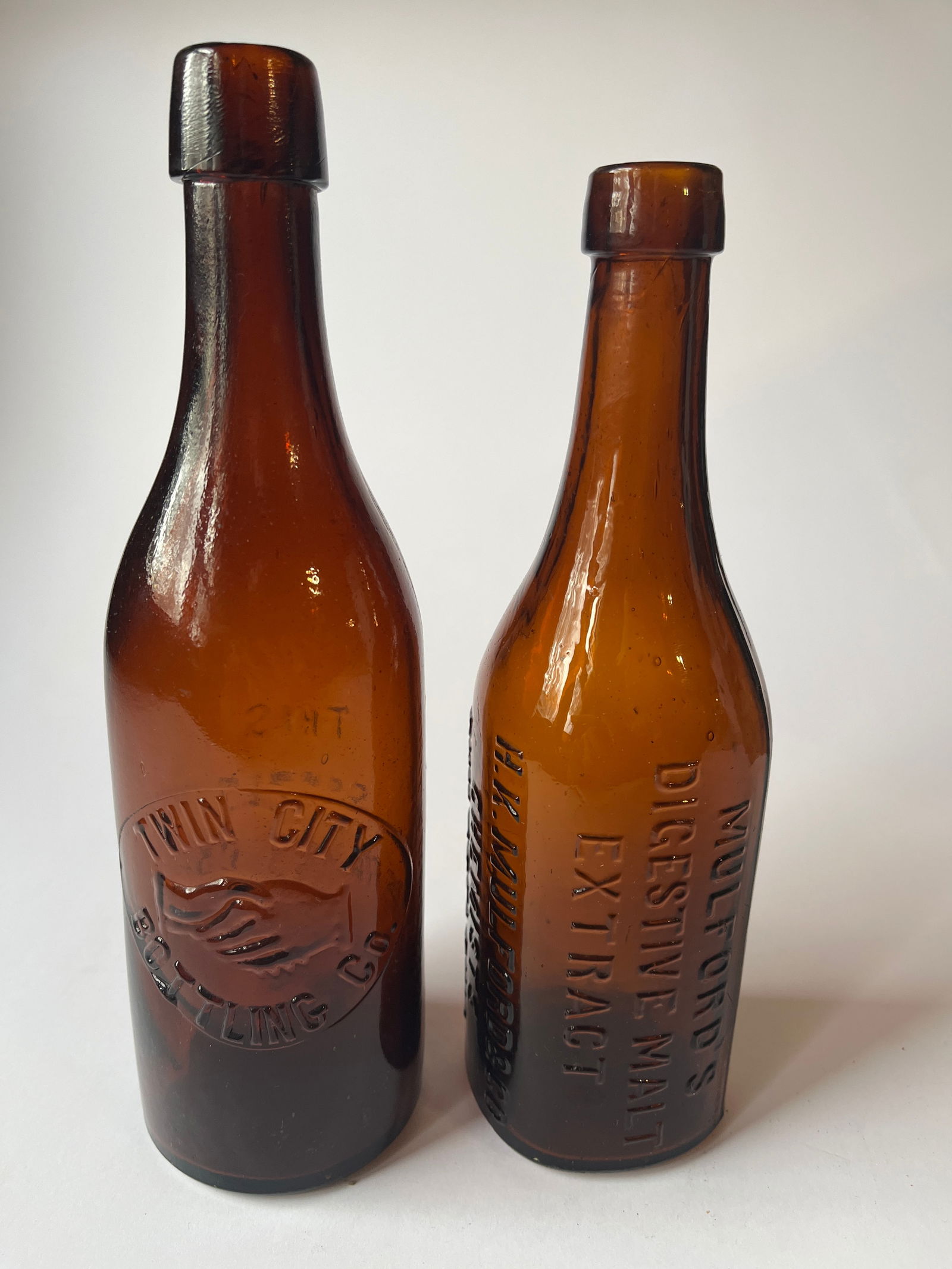 Lot of 2 amber embossed bottles, A Twin City Bottling Co and a Mulfords Extract. (1 of 5)