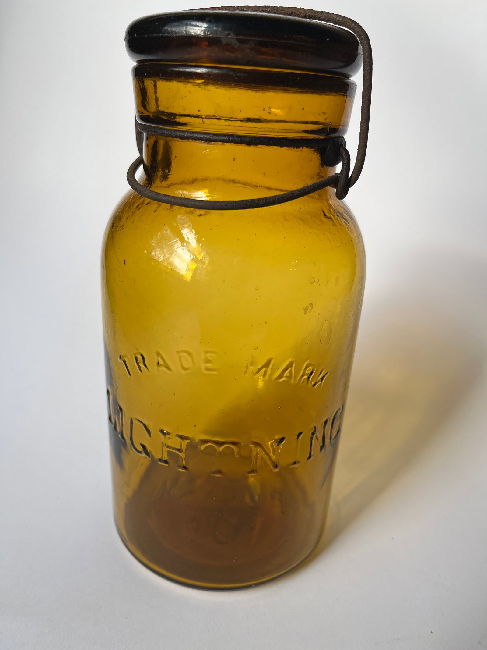Quart amber TRADE MARK LIGHTNING: Quart amber TRADE MARK LIGHTNING. Yellow amber. No damage. Slightly darker lid.