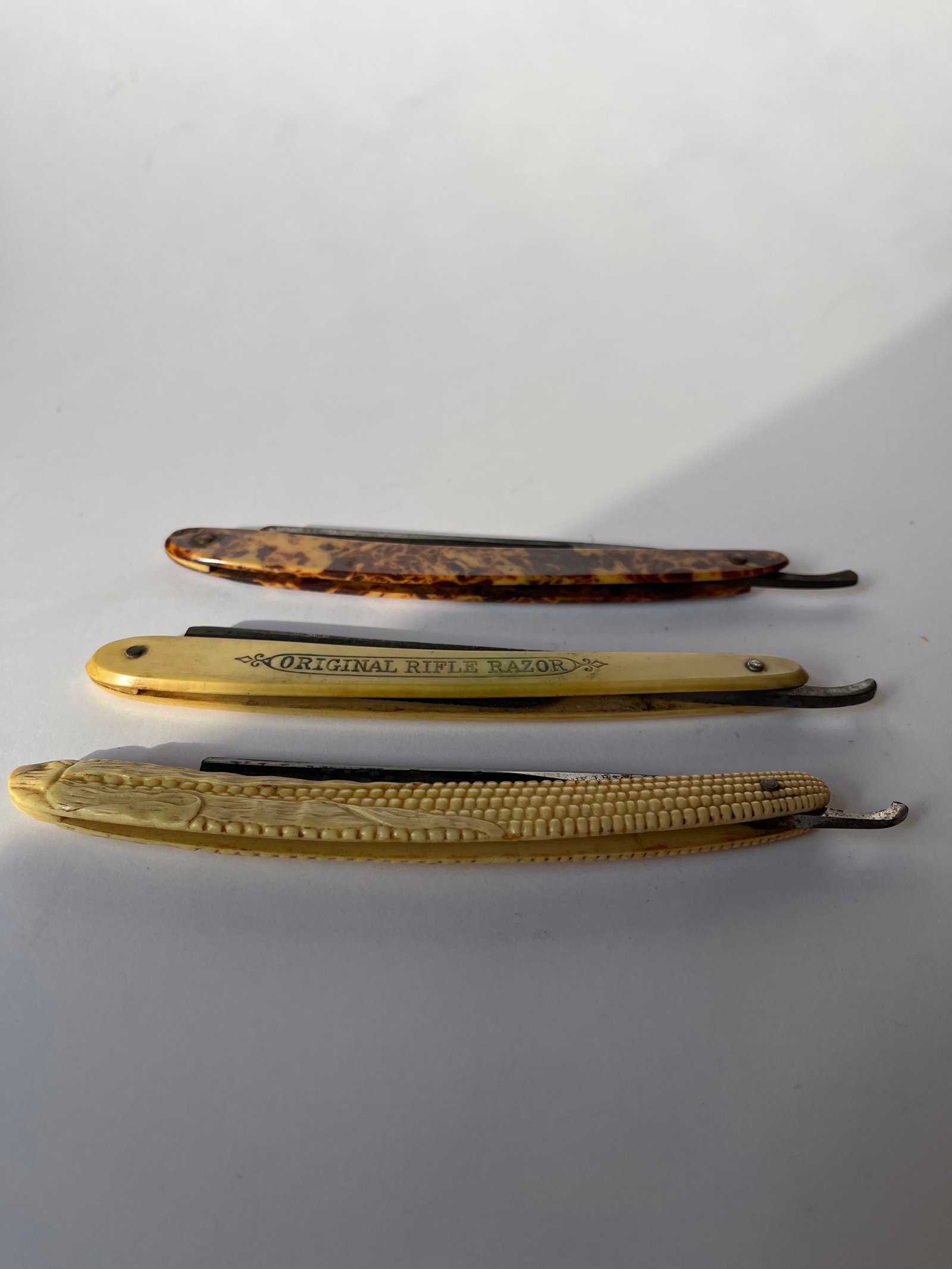 Lot of 3 straight razors..: Three straight razors. The first is an ear of corn handle with a blade that reads Our Beauty. Blade has 2 chips. The second one has Original Rifle Razor debossed on the handle. Blade is a little hard 