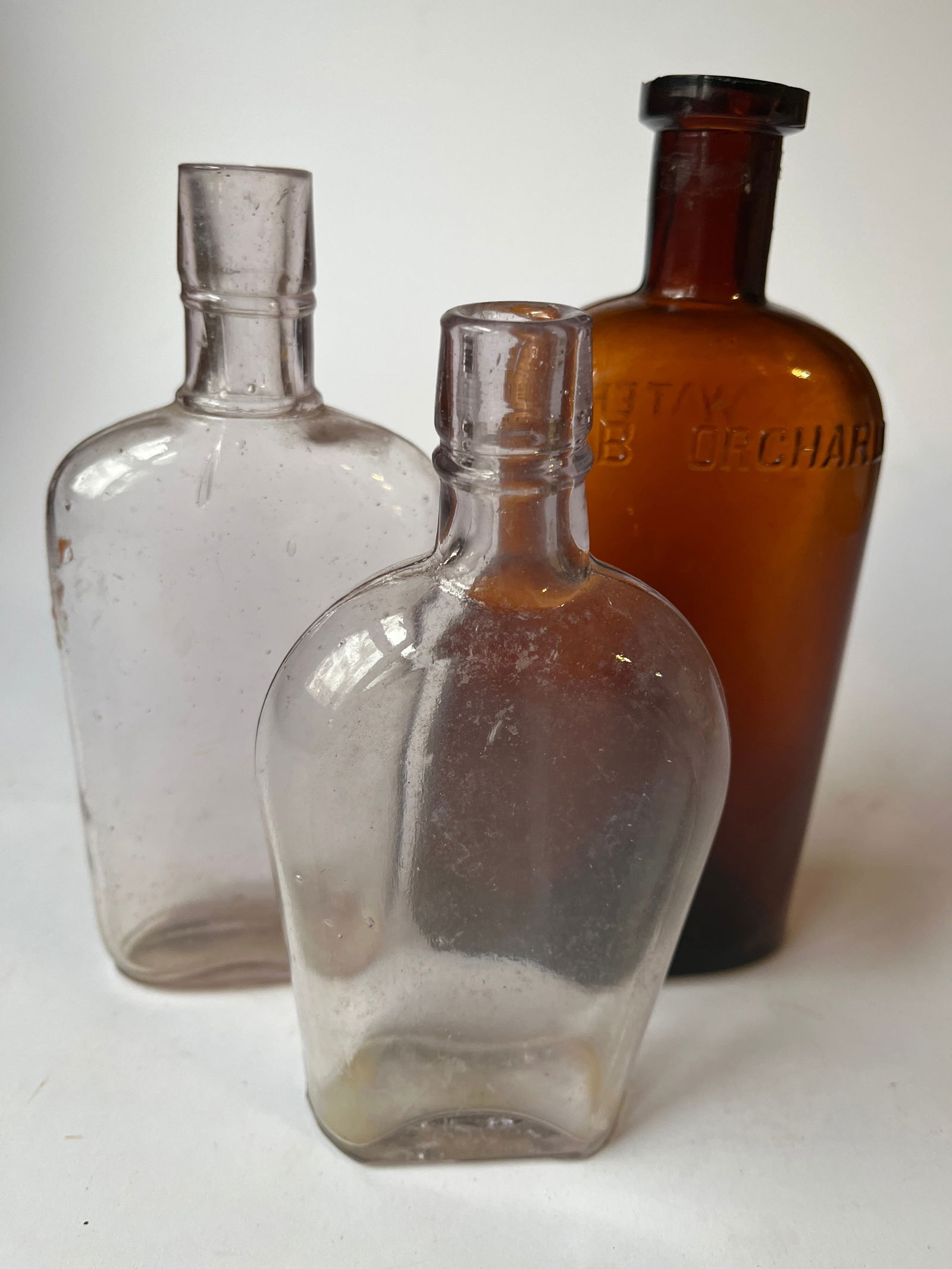 Lot of 3 flask shaped bottles. One embossed CRAB ORCHARD WATER. (1 of 3)