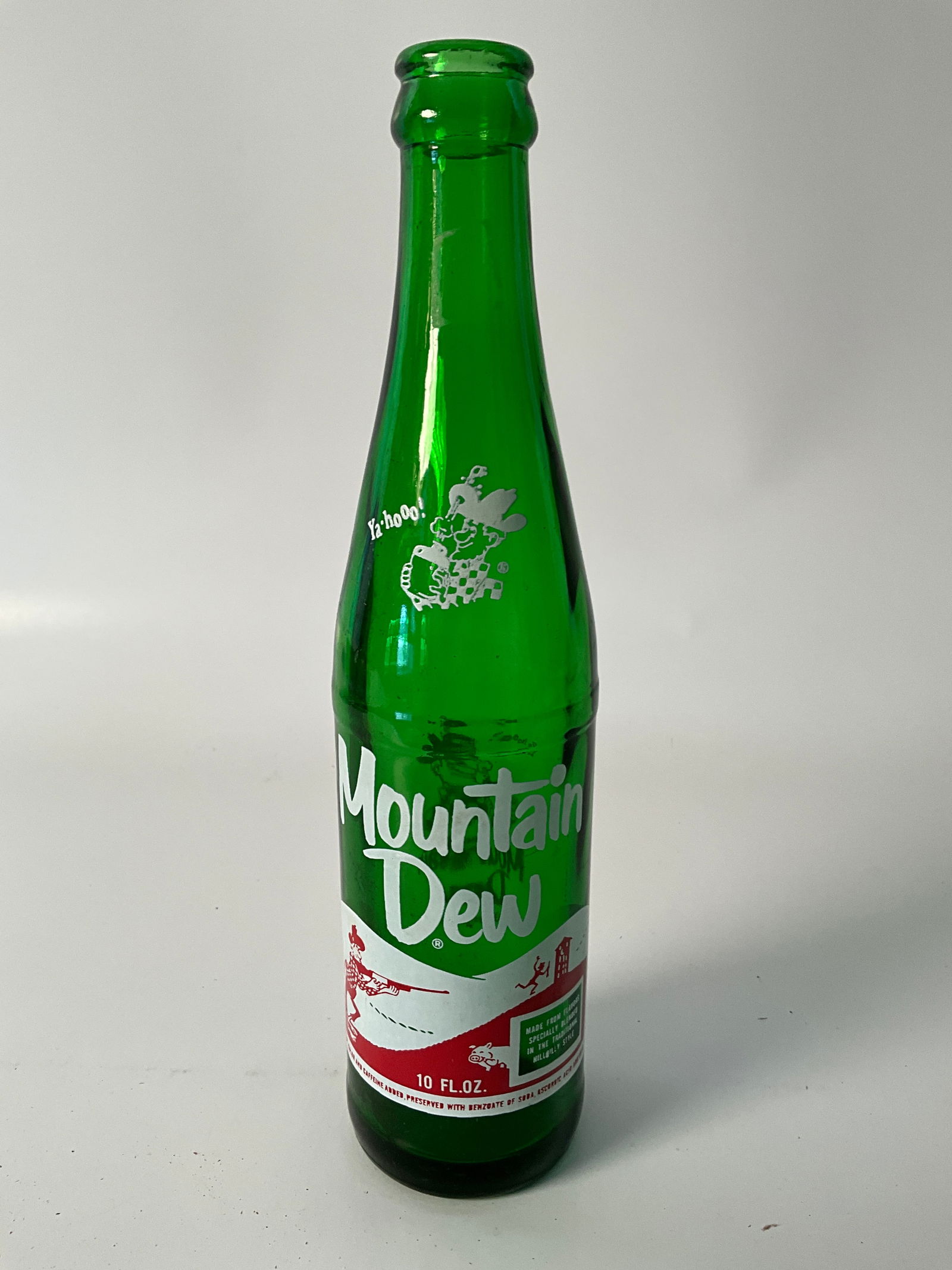 Mountain Dew Hillbilly with Laughing Pig 1968: Moutain Dew Hillbilly bottle with laughing pig. most bottles have a pig peeking around the corner, while this pig is laughing. 10oz.