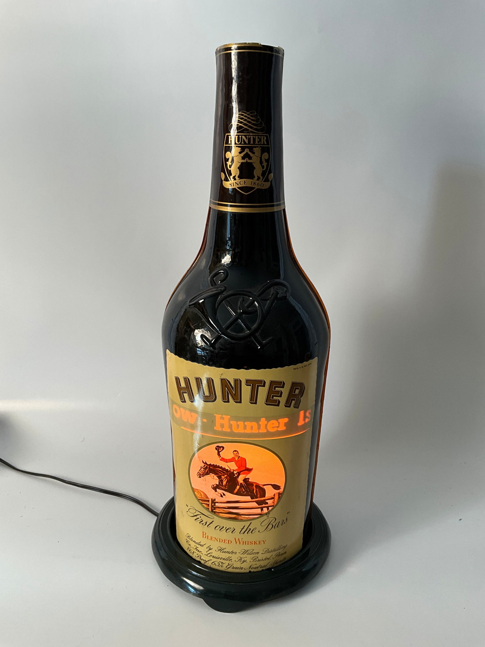 Hunter-Wilson Distilling Co., Louisville, Ky and Bristol, Penn. Whiskey Bottle Light-Up Revolving: Hunter-Wilson Distilling Co. light-up revolving whiskey bottle advertisement. Bottle is plastic. Great showpiece for any bar! The warm-colored light is just as smooth as the whiskey! Measures 22" tall