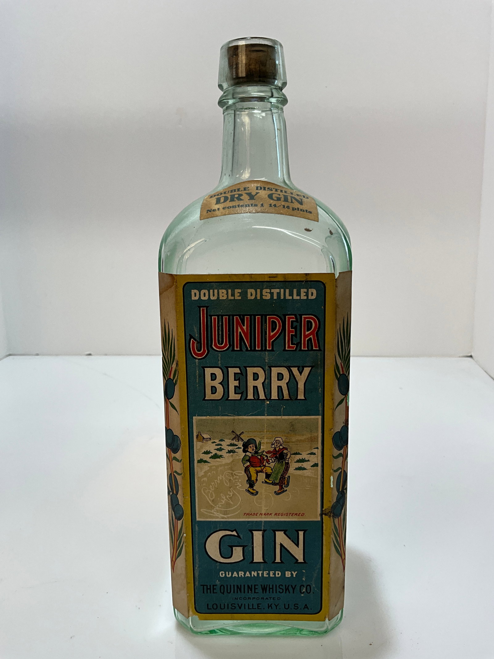 Juniper Berry Gin, Quinine Whiskey Co., Louisville Kentucky, Full Label: A machine made bottle with the embossing of Juniper Berry Gin, Bottled By, Quinine Whiskey Co., Louisville Ky, with Full Label. A really nest bottle with a lot of embossing on one panel, and then a la
